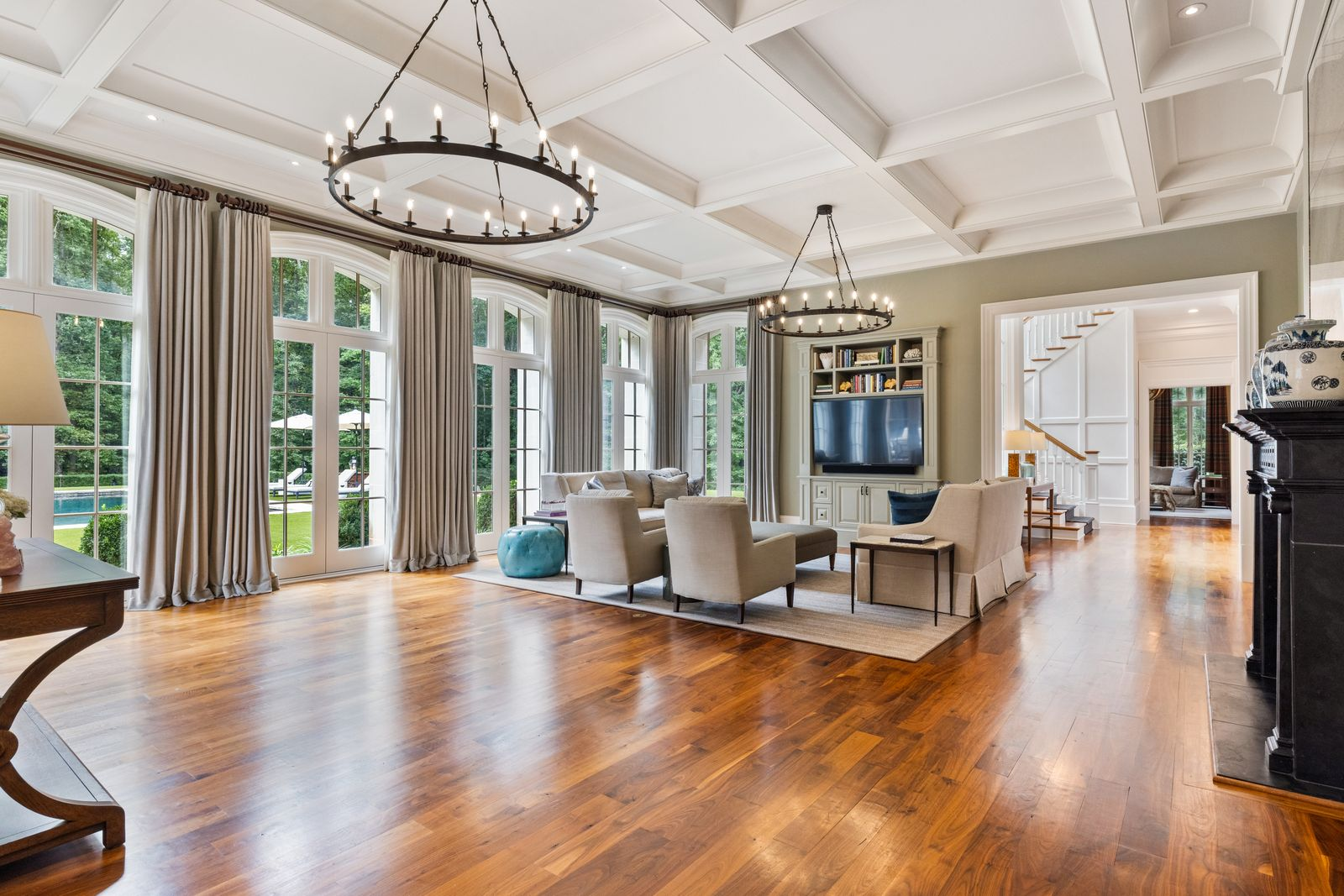 A full wall of tall arched windows and French doors brings in natural light and opens the room visually to the lawn and pool, giving the entire space easy access to the grounds.