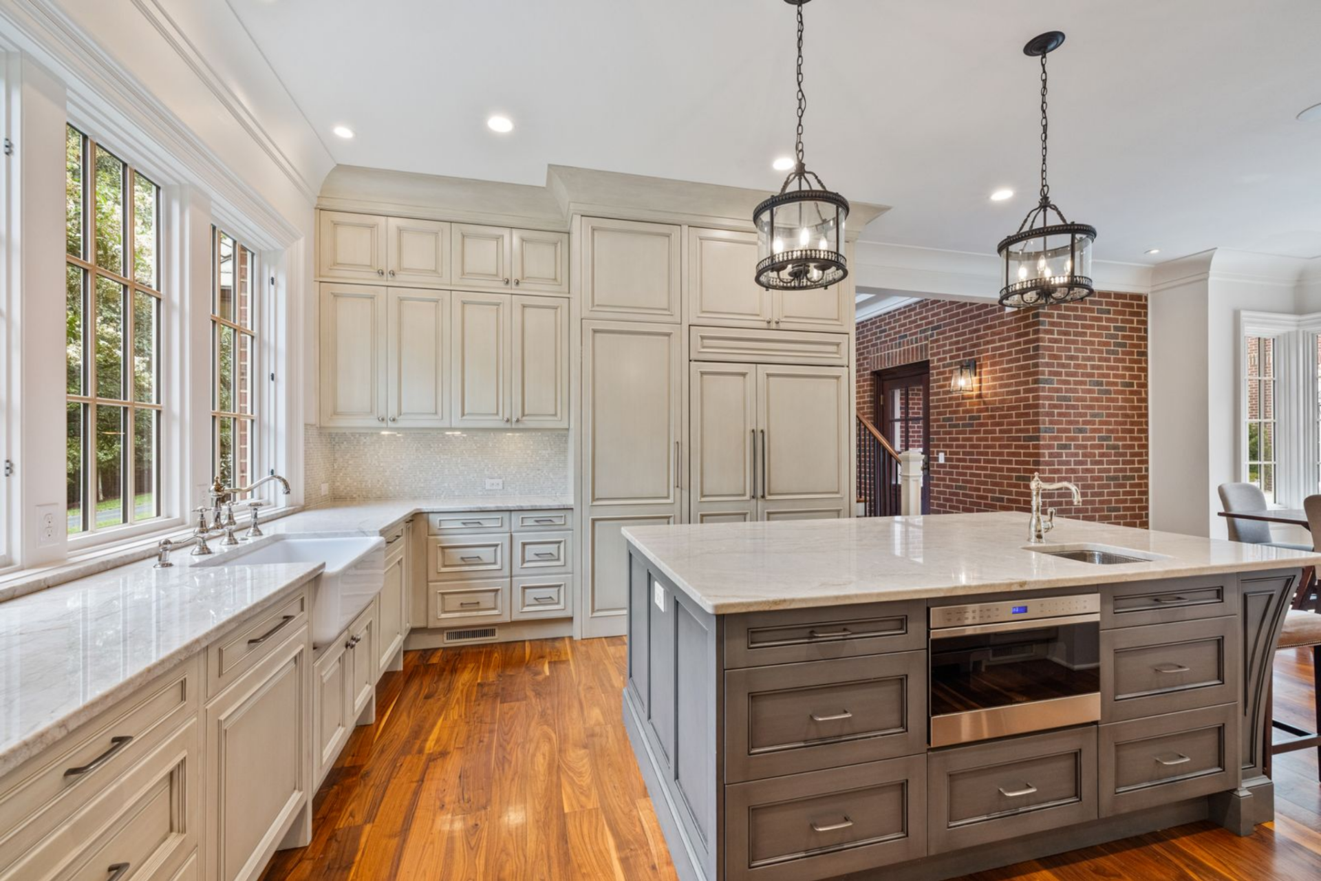 Around the perimeter, the room is lined with light-toned cabinetry, stone countertops, and a full wall of built-in storage that keeps the layout clean and symmetrical. 