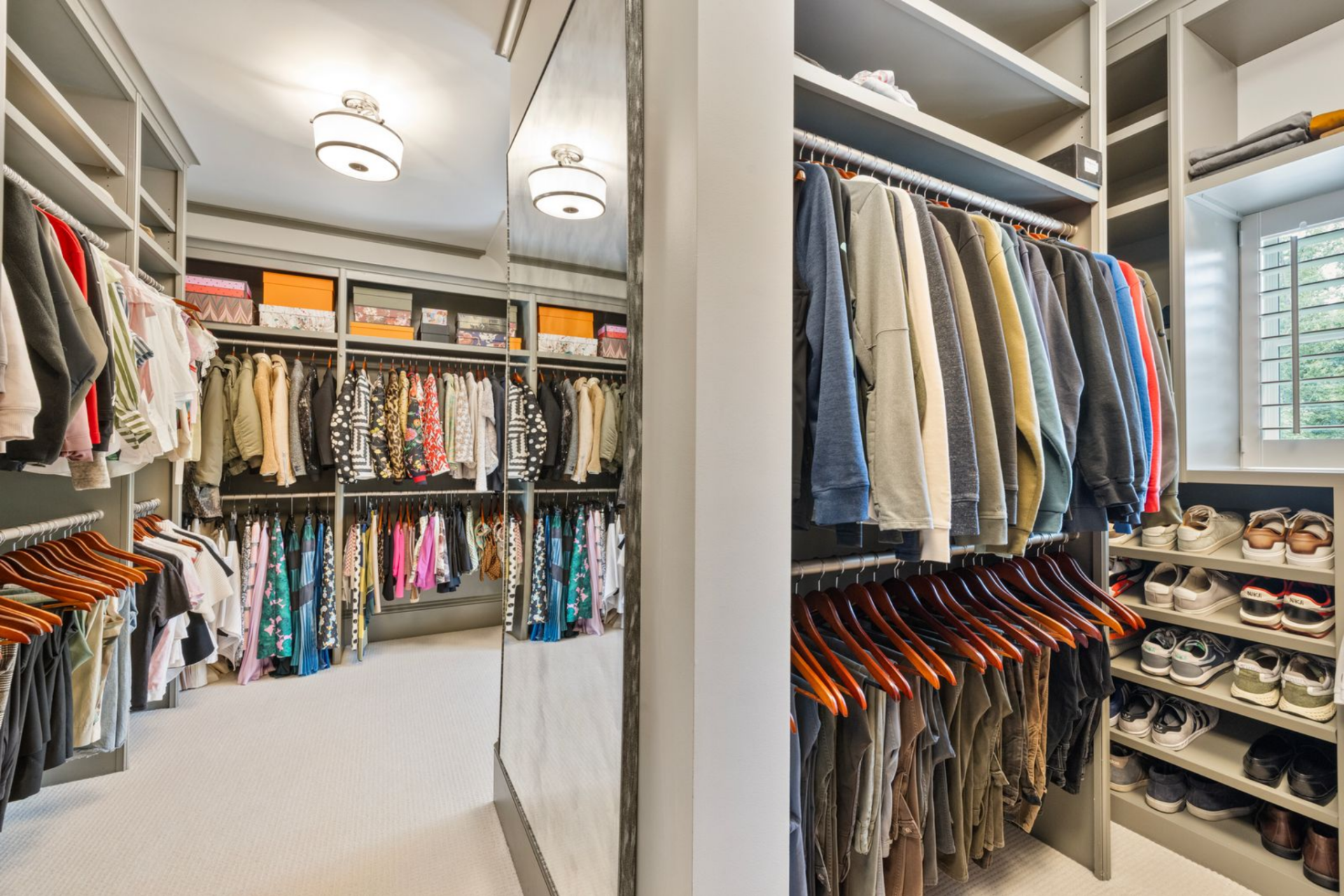 At the back of the bathroom, the suite moves into a walk-in closet with built-in shelving, hanging storage, and dedicated sections for clothing and shoes on both sides. 