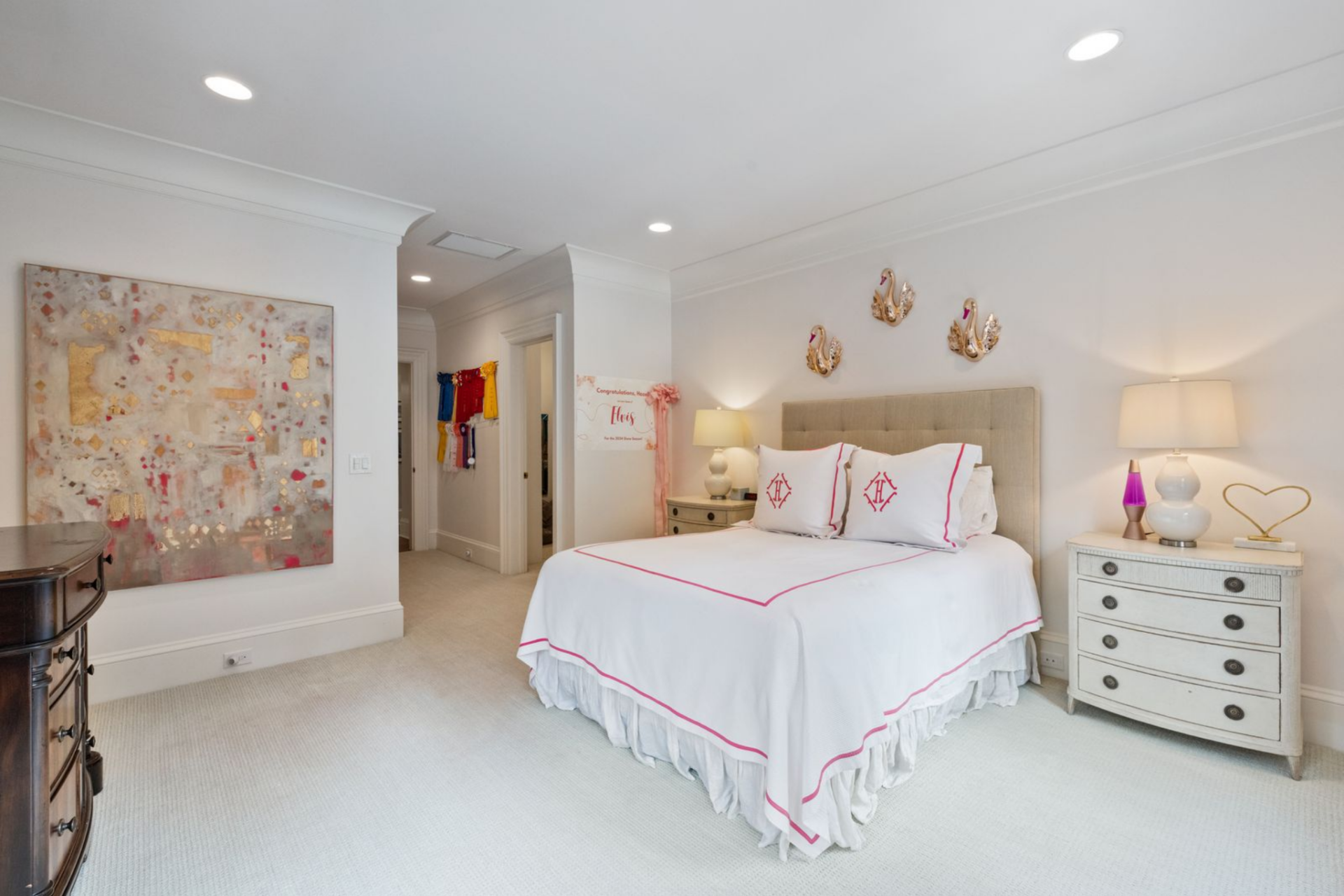 The bed is centered along the main wall with matching nightstands on either side, while layered bedding and subtle pink accents add color without overwhelming the space.