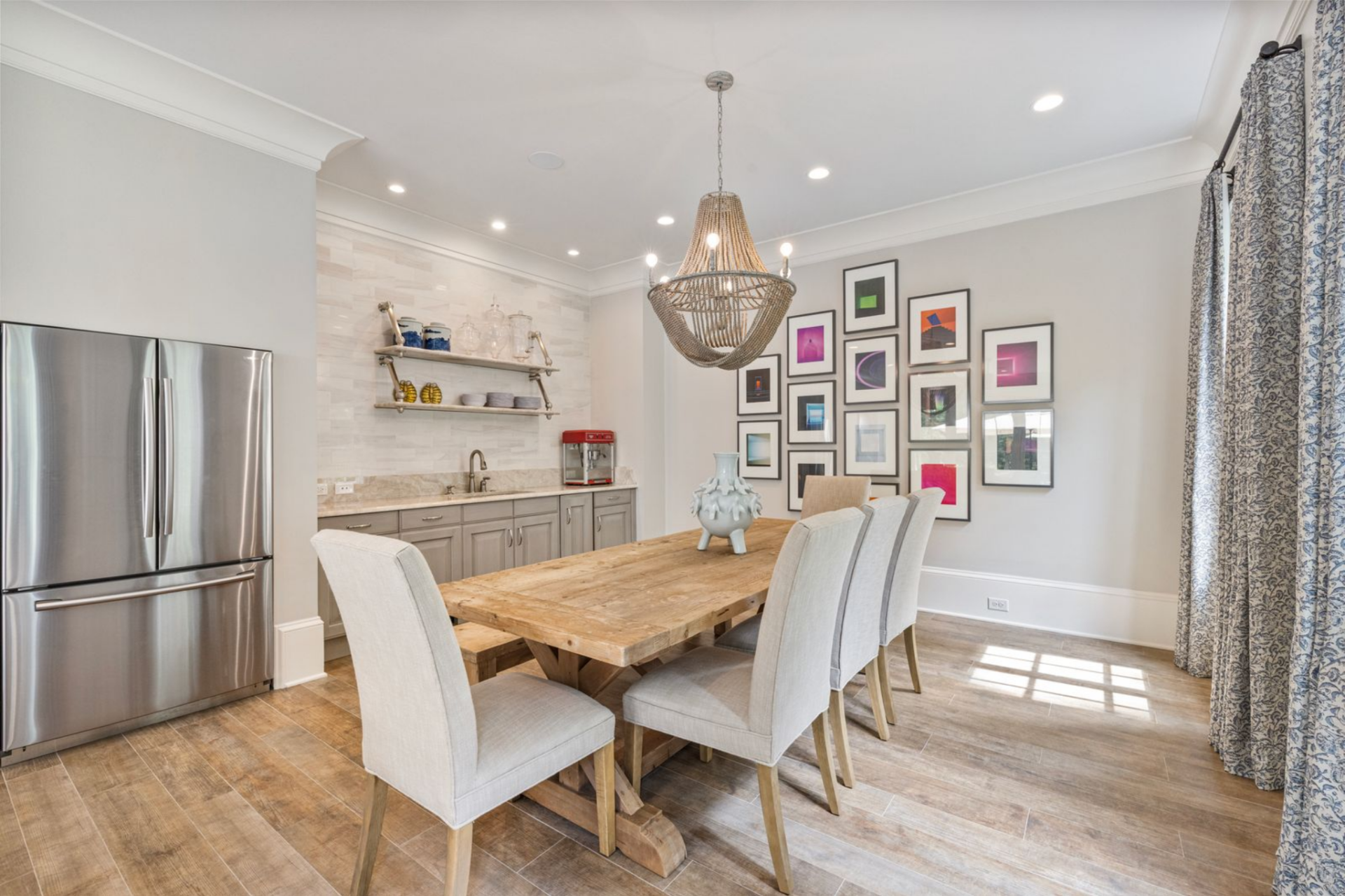 A few steps away, the dining area sits right next to a kitchenette and full-size fridge with a long wood table surrounded by upholstered chairs.