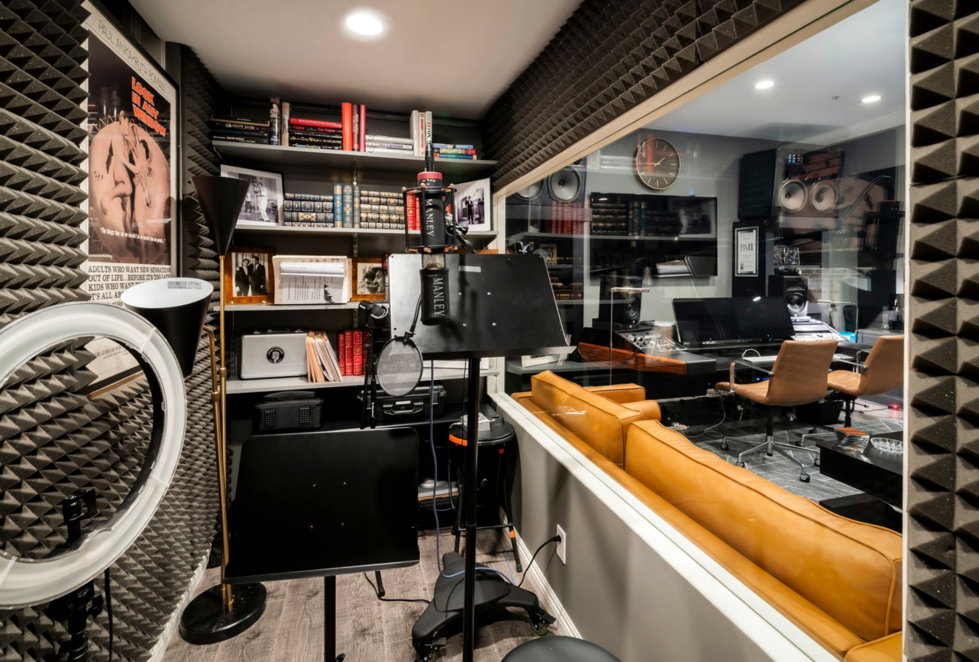 The setup continues into a separate vocal booth, enclosed in glass and treated with acoustic paneling.
