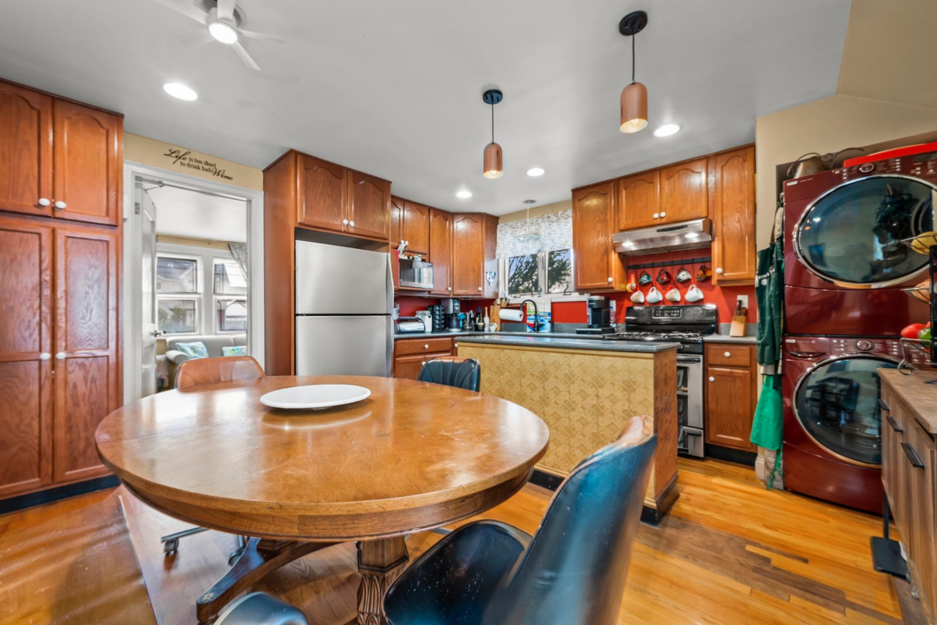 On the other side of the first floor, the kitchen combines a full wall of warm wood cabinetry with a compact U-shaped workspace.