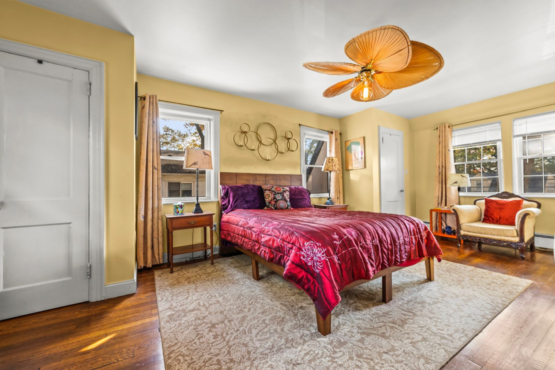 Stepping up to the second floor, the primary bedroom opens with the bed positioned centrally between two windows. 