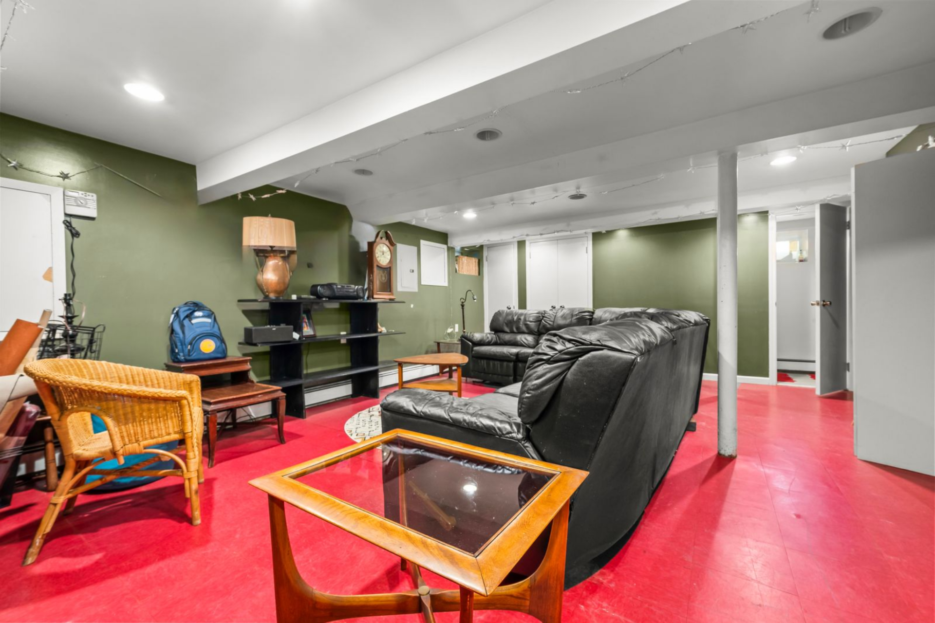 The room consists of one open area with red-painted floors, olive green walls, and low ceilings that keep the layout straightforward and utilitarian.