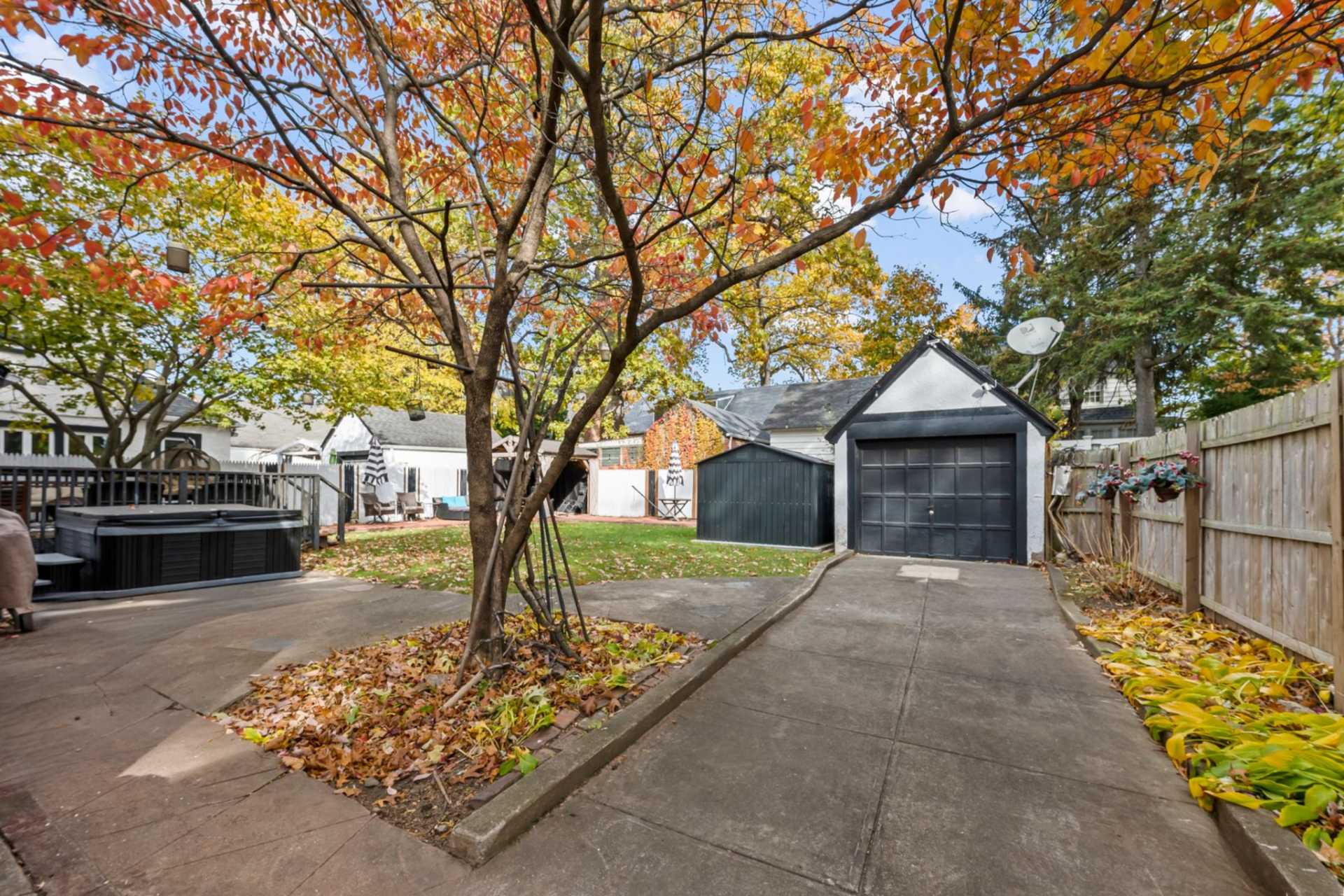 At the back of the property, a paved driveway runs along the side yard and opens to a detached garage positioned at the back of the home.