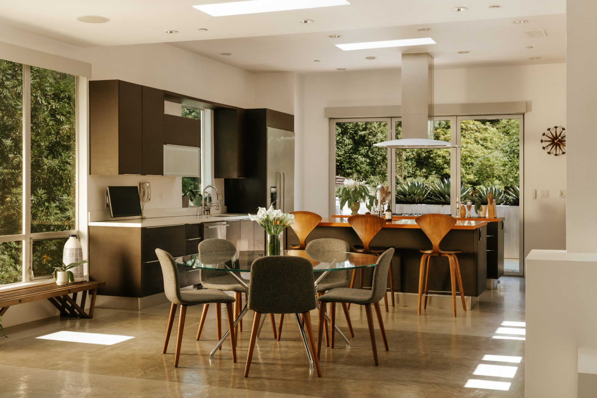 A few steps away, the kitchen is organized around two parallel islands that define the space, each finished with warm-toned countertops and surrounded by dark cabinetry.