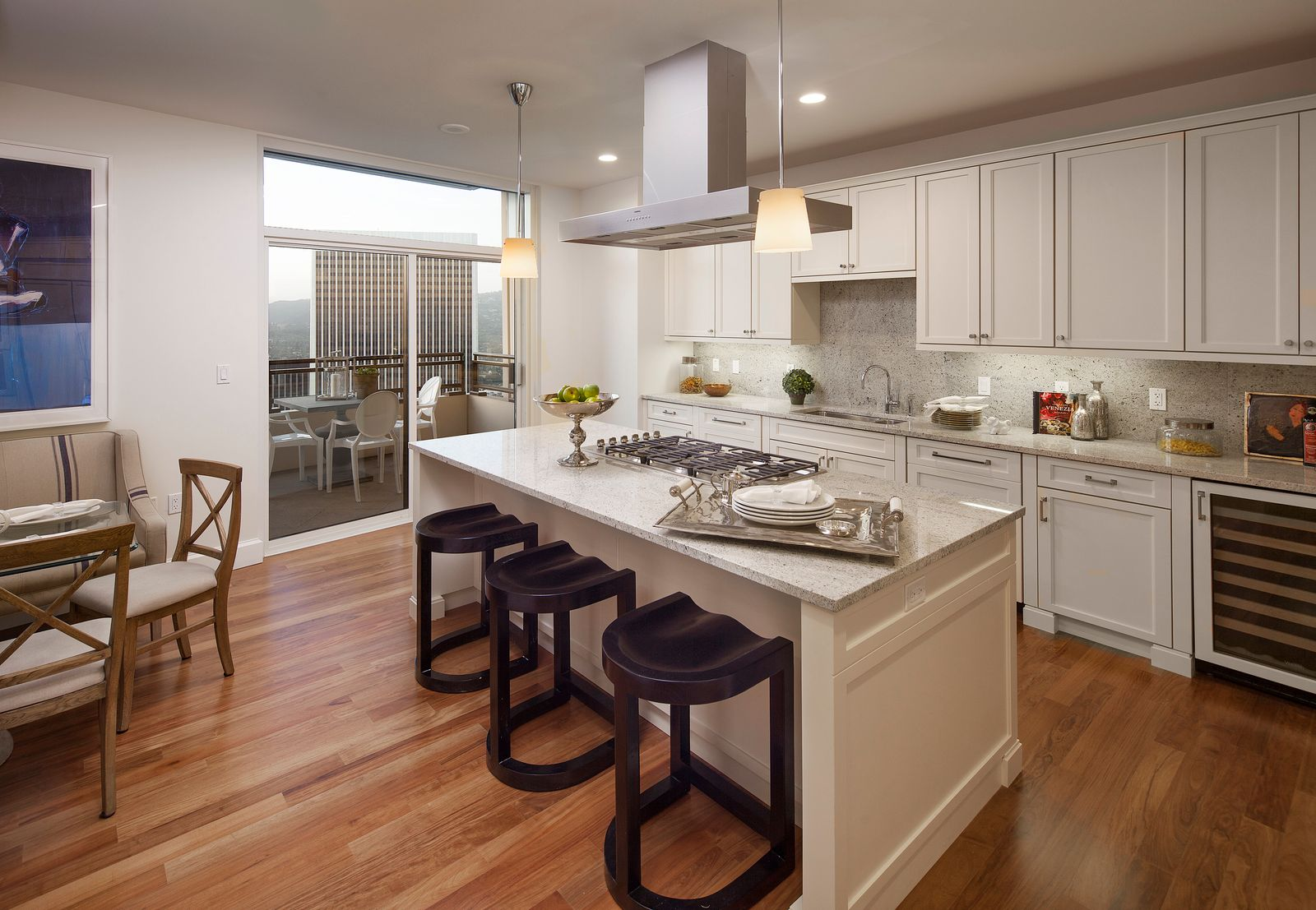 In the next room, the gourmet kitchen has a large center island with bar seating topped with stone counters and a built-in cooktop, while surrounding cabinetry runs wall to wall.