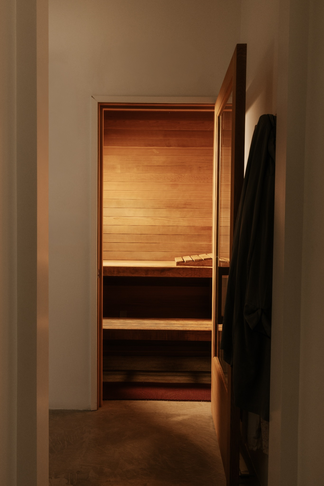 Just off the bath area, the bathroom features a sauna with full wood paneling and stacked built-in bench seating.