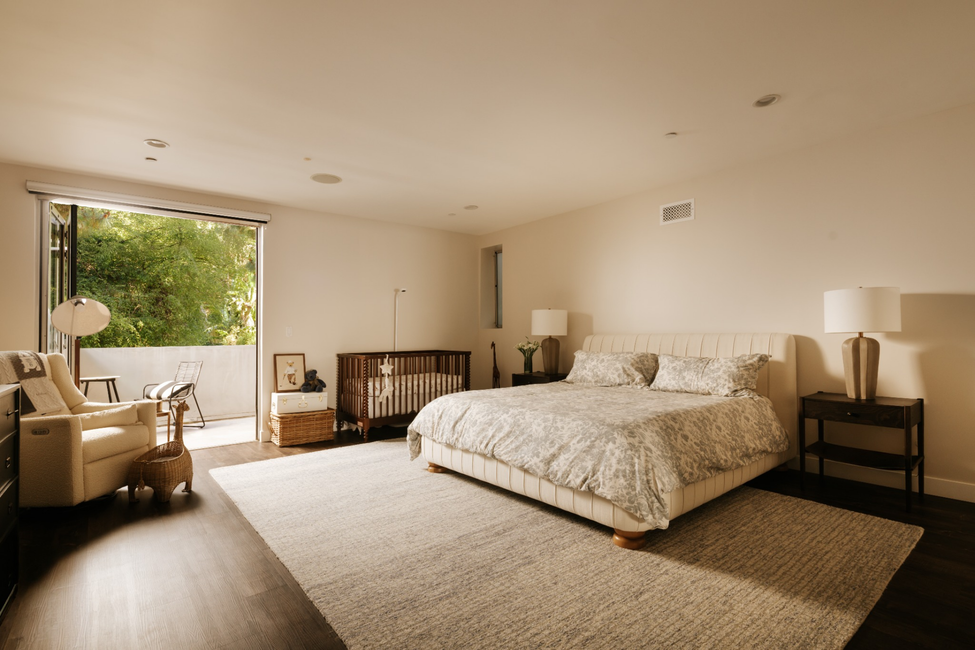 The bedroom itself is simple and spacious, centered on a large upholstered bed set against a neutral wall with matching nightstands on either side.