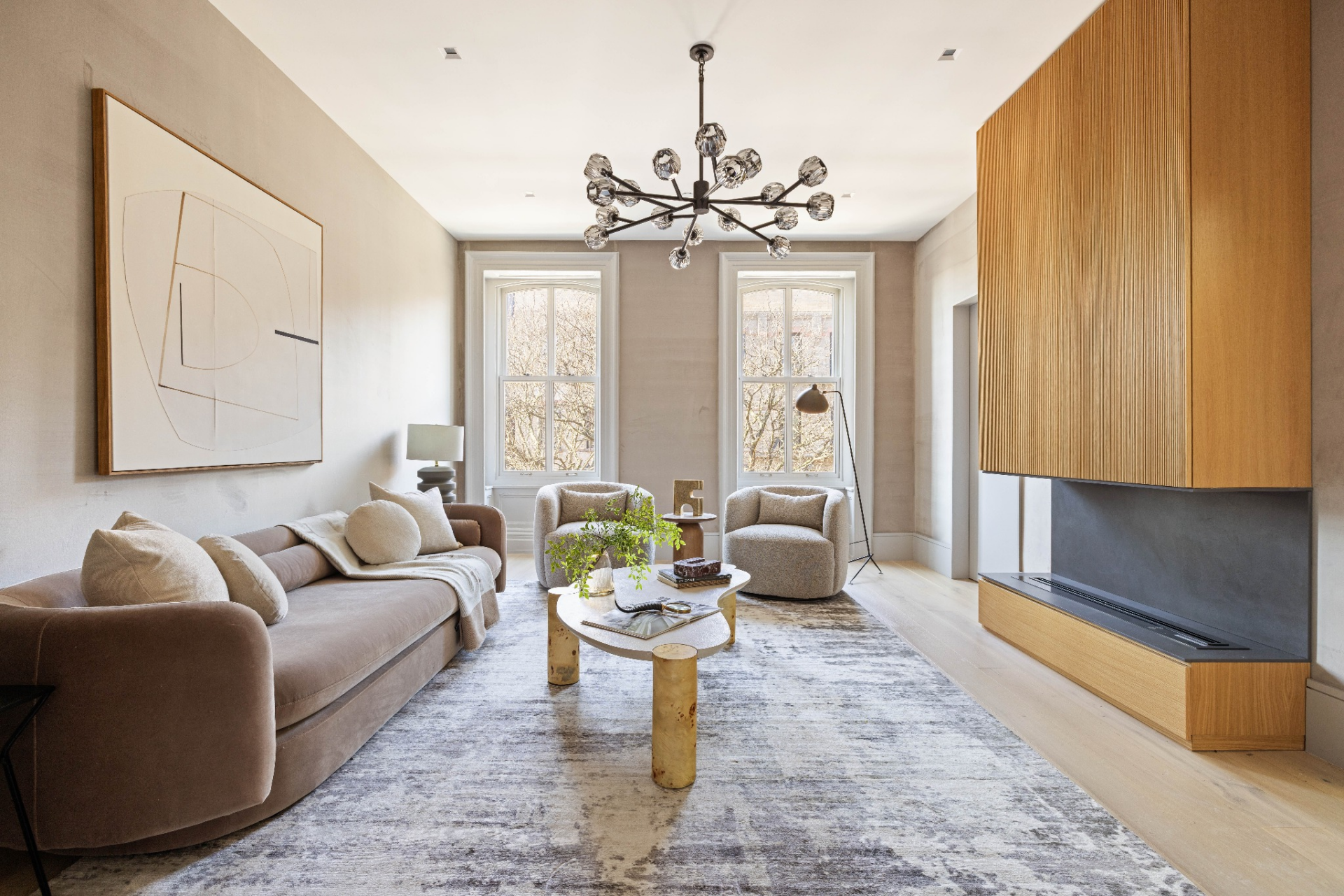 A sofa and pair of chairs are arranged around a central table, while a built-in fireplace wall runs along one side, adding a focal point without breaking the clean lines of the room.