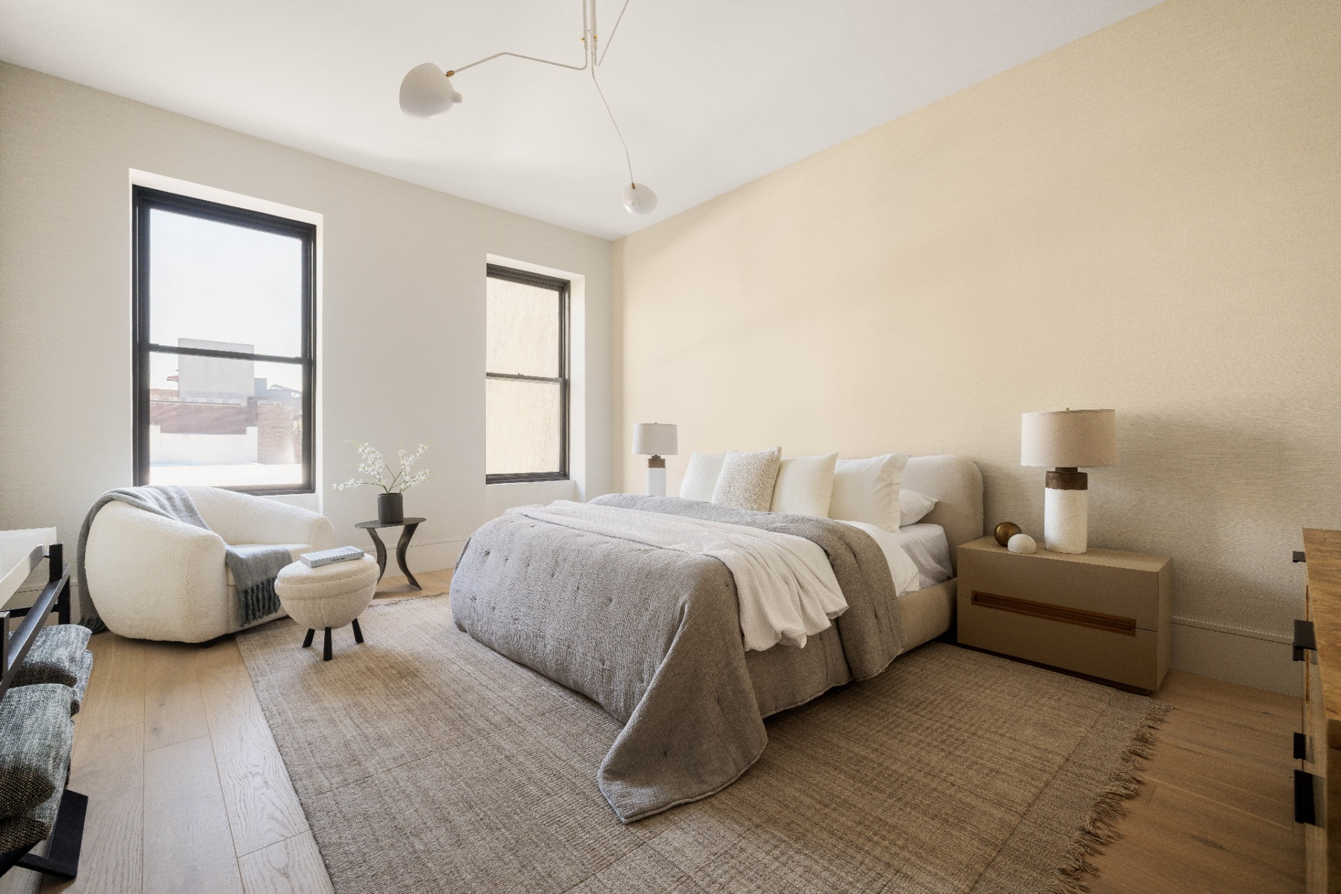 The layout is straightforward, with the bed centered against the main wall, framed by low nightstands and matching lamps, while two windows bring in natural light from the street side.