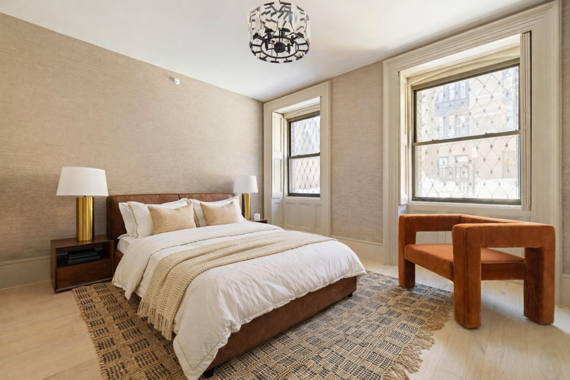 Two windows framed by traditional millwork define the room, bringing in filtered light while adding architectural detail, while the furniture remains minimal and intentional.