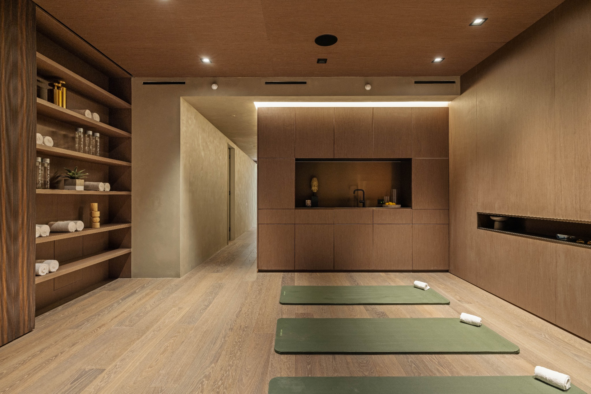 Built-in shelving lines one side with room for towels and accessories, while a wall of cabinetry at the far end conceals storage and a wet bar.