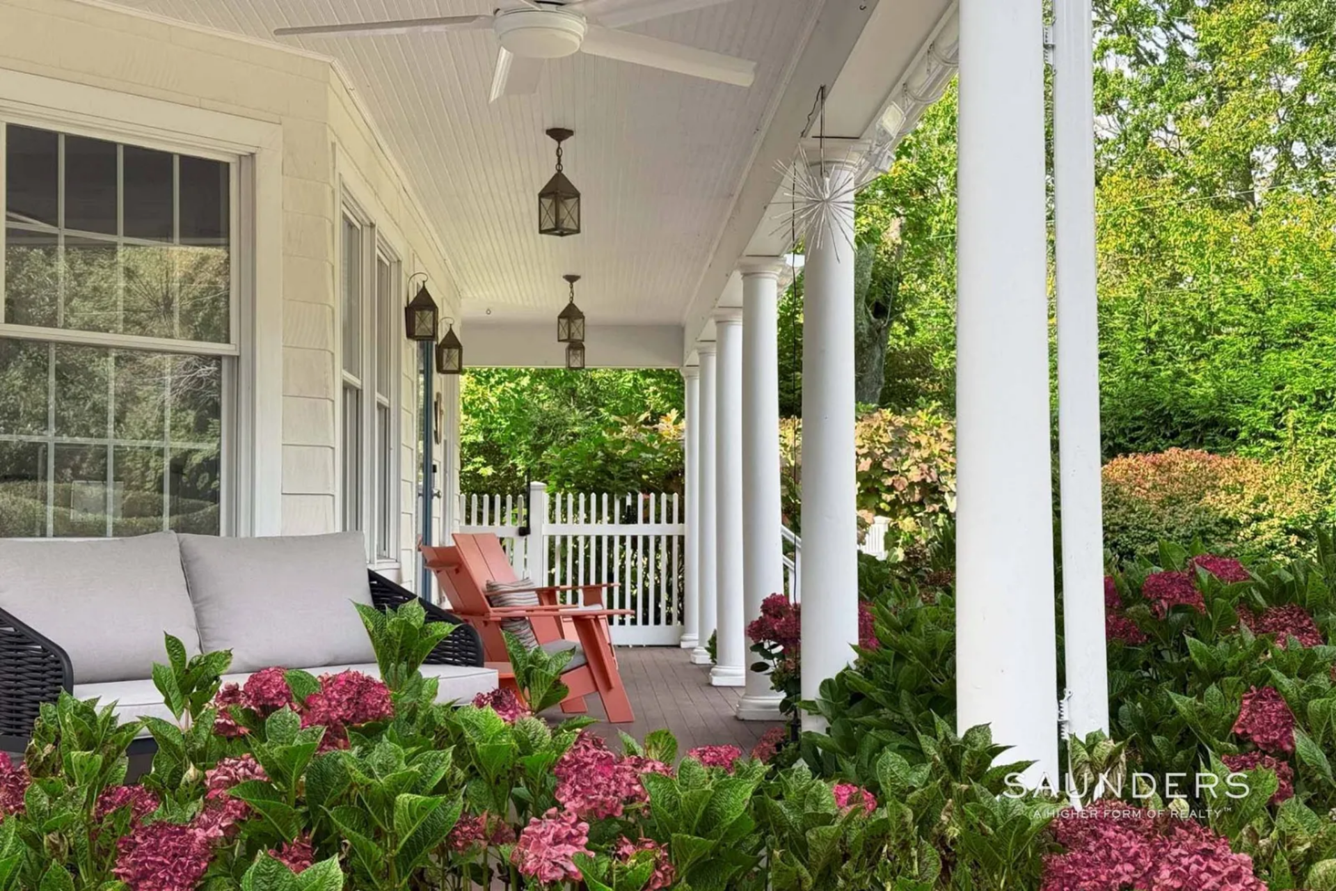 Painted wood decking, hanging lanterns, and ceiling fans make the porch a relaxing spot to take in the fresh air before stepping inside the house.