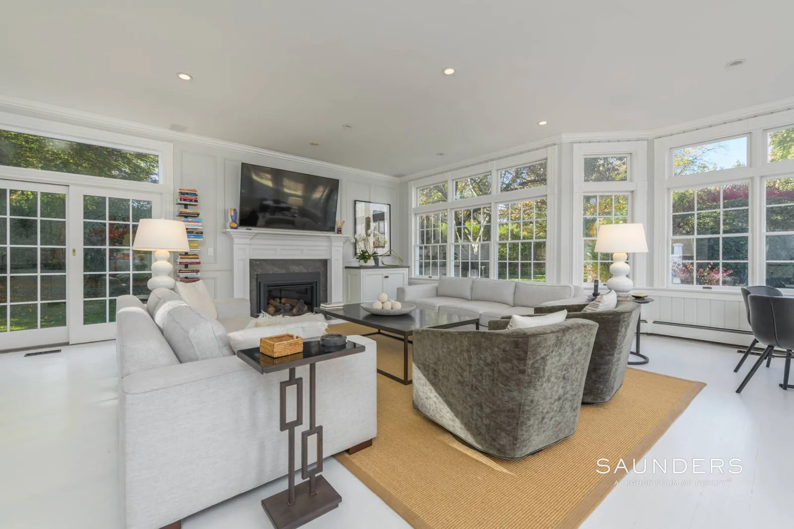 Stepping inside, the living room opens as a bright corner space organized around one of the home’s original fireplaces, which remains the central feature along the main wall. 