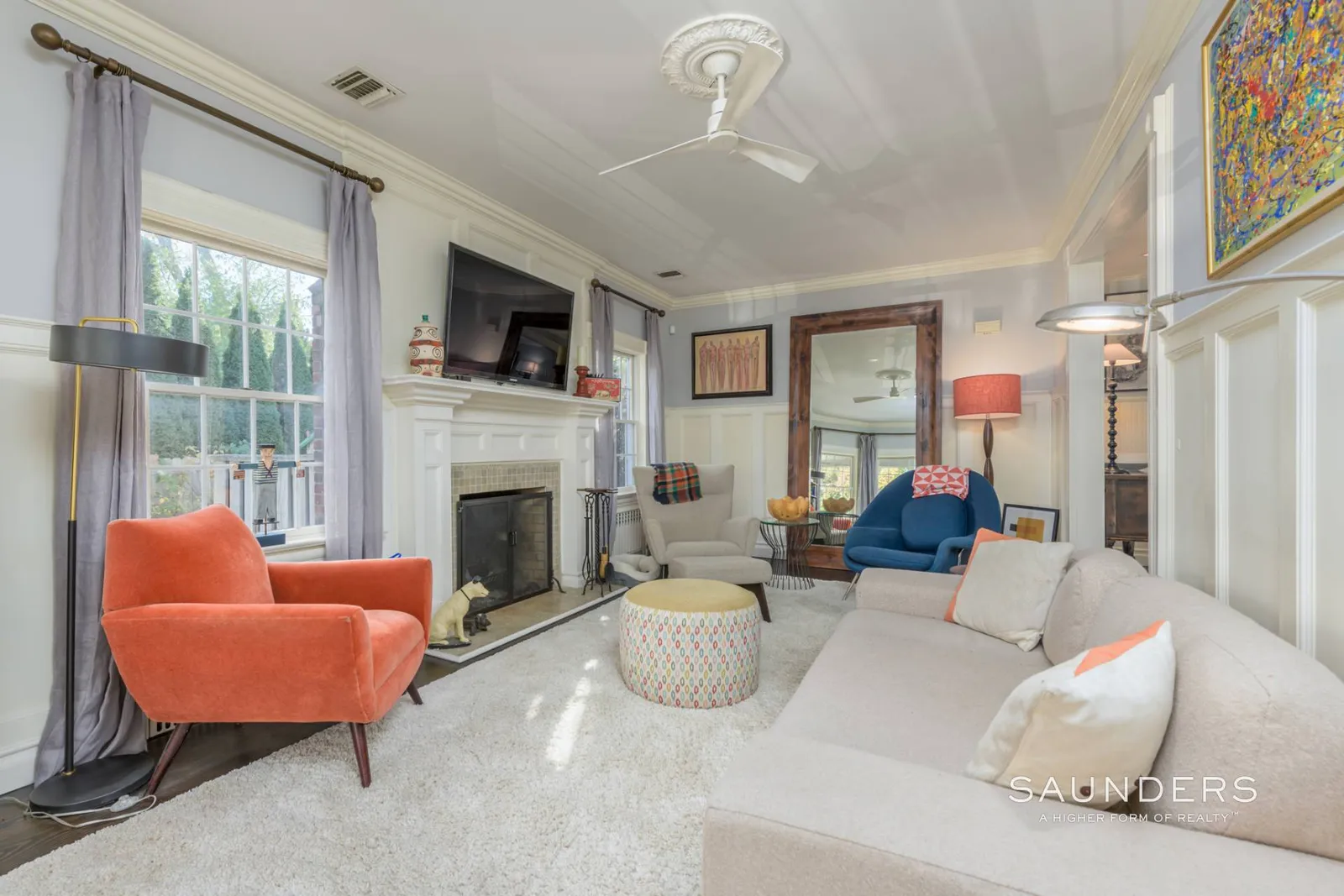 Just beyond the main living room, the den shifts into a more enclosed space, again organized around an original fireplace set into a white mantel along the central wall. 