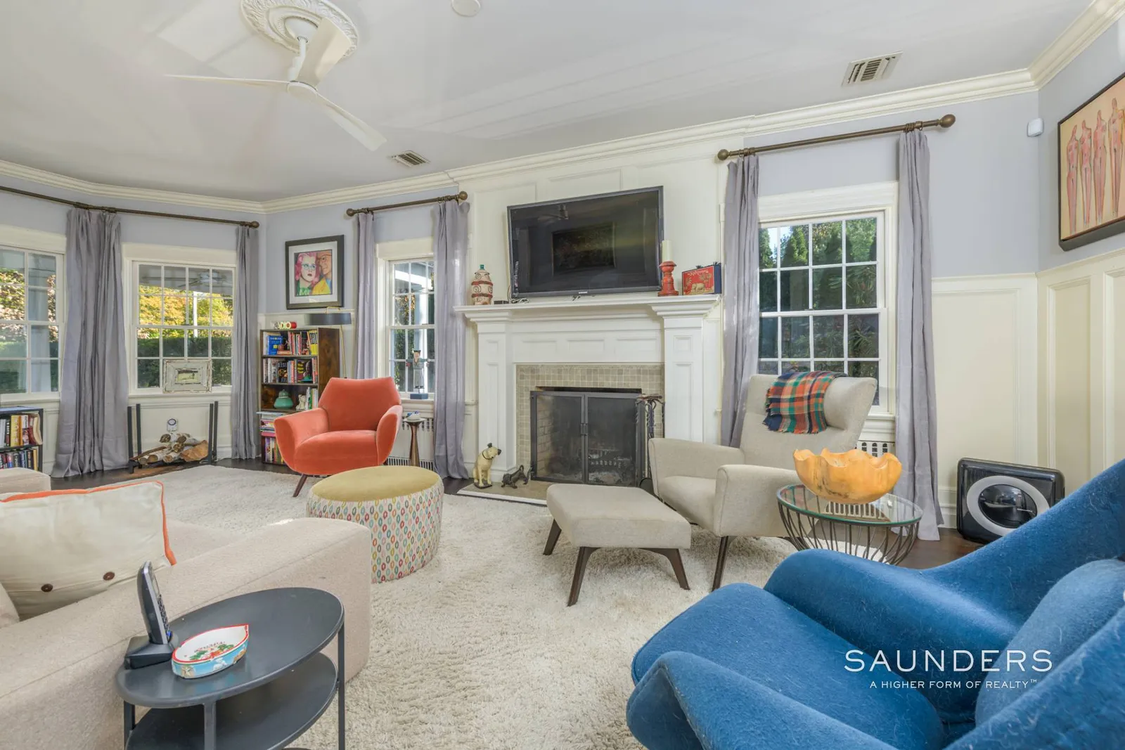 Seating is pulled in closer here, with a sofa, armchairs, and an ottoman arranged directly around the hearth, creating a tighter, more contained layout.