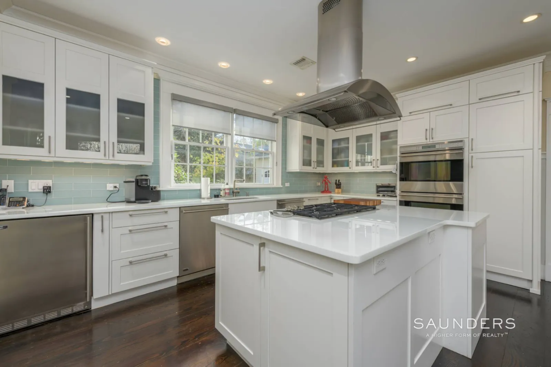 White shaker-style cabinetry wraps the room from floor to ceiling, while the pale blue tile backsplash and dark wood floors give the space a cleaner, more updated look.