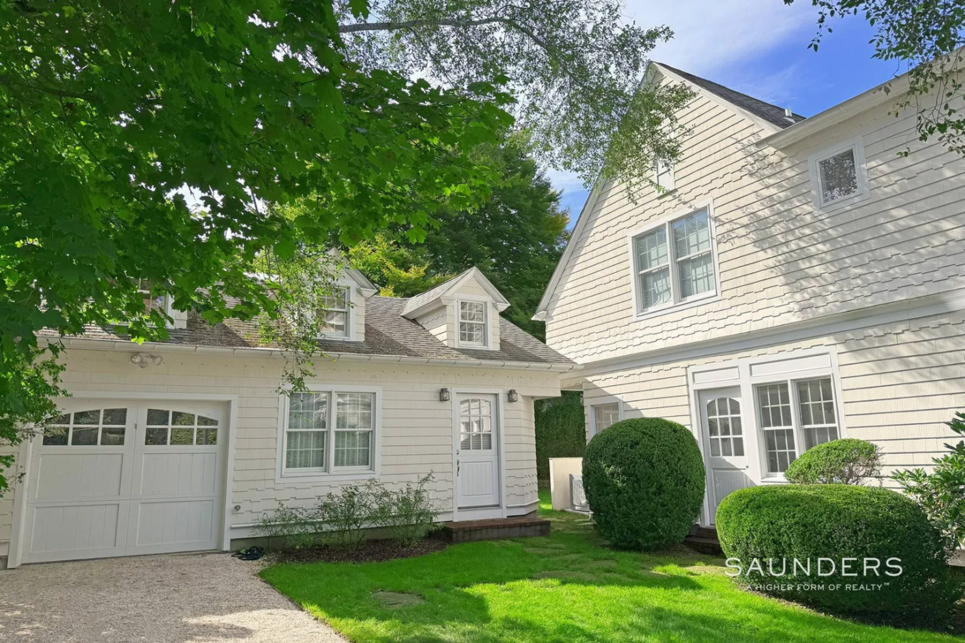 Sitting next to the main house, the detached studio cottage sits at the end of its own gravel driveway and clipped lawn that make it look like a mini house.