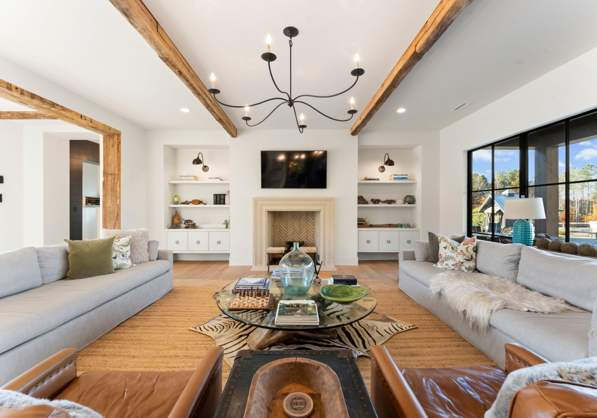 The room is arranged around a carved fireplace with a herringbone firebox, framed by built-in shelving that keeps the wall balanced without adding visual clutter. 