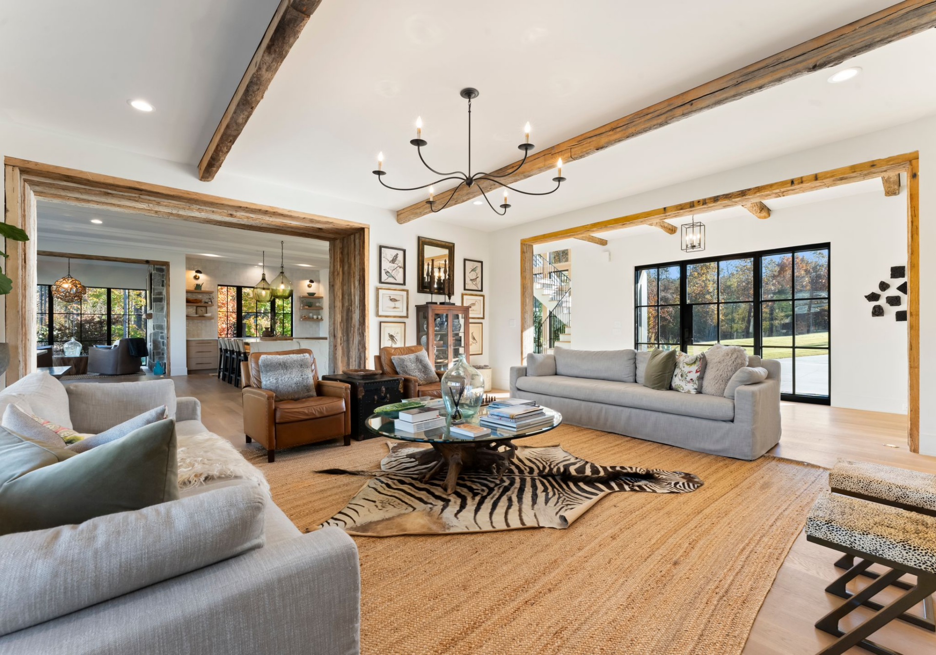 A pair of long sofas face one another across a glass coffee table, with leather chairs at the front of the seating group, creating a layout that feels made for conversation as much as everyday lounging.