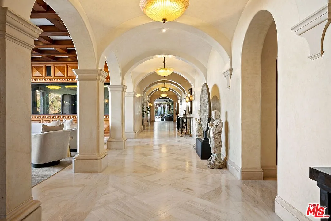 From there, the layout extends into a 100-foot gallery hall where repeating arches, columns, and polished stone floors guide you into the home's main living spaces.