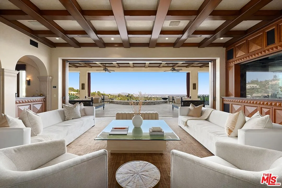 Along one side, the wall fully opens to a covered terrace, turning the living room into an indoor-outdoor space with direct access to the exterior lounge and city views.