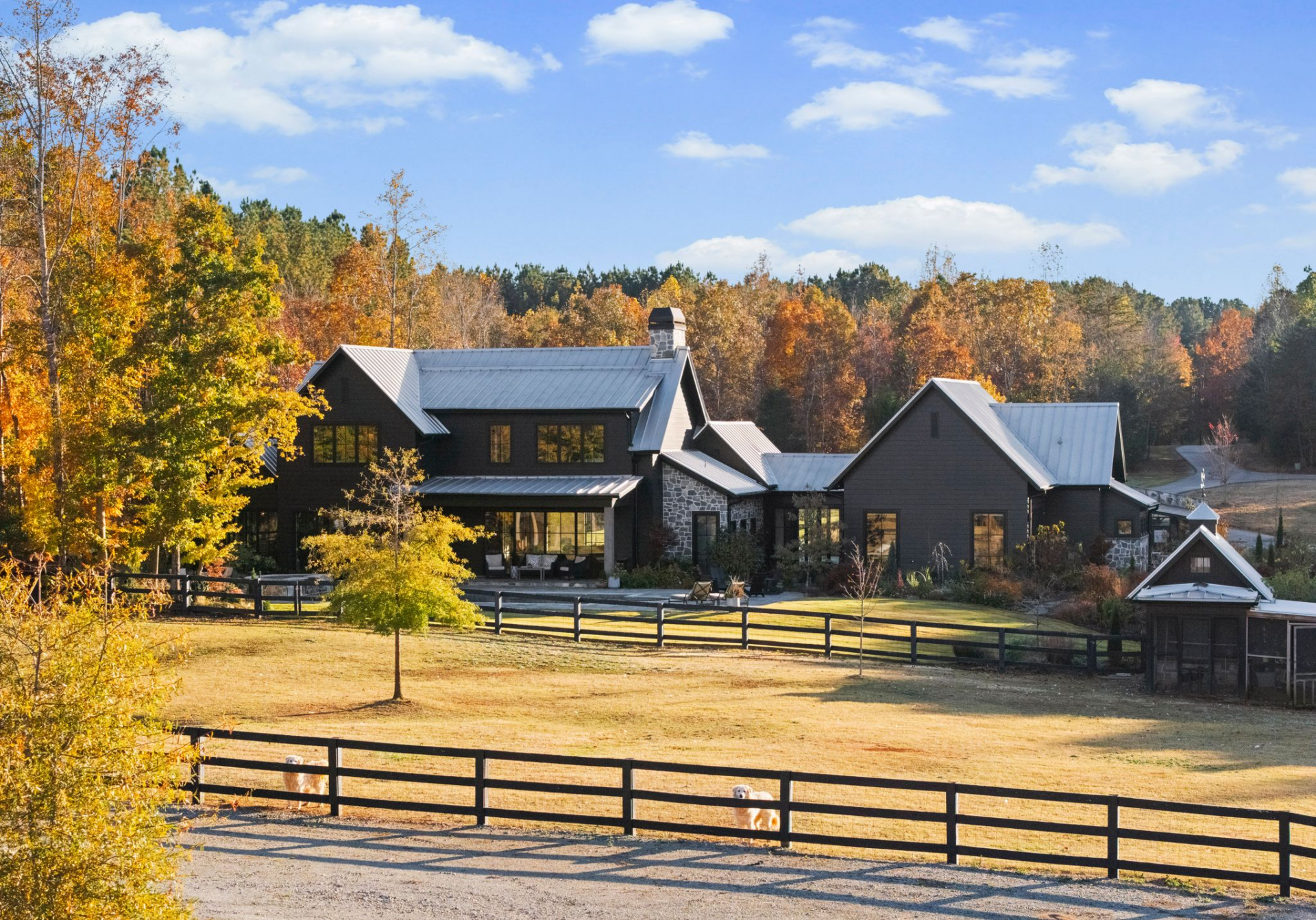 Across the broader acreage, the property shifts into open, functional land with fenced pastures and a dedicated barn structure. 