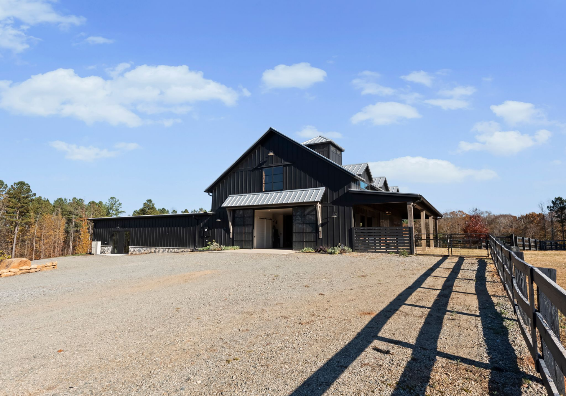 The barn mirrors the home’s dark exterior and metal roofing, tying it architecturally to the main residence while serving as a working space.