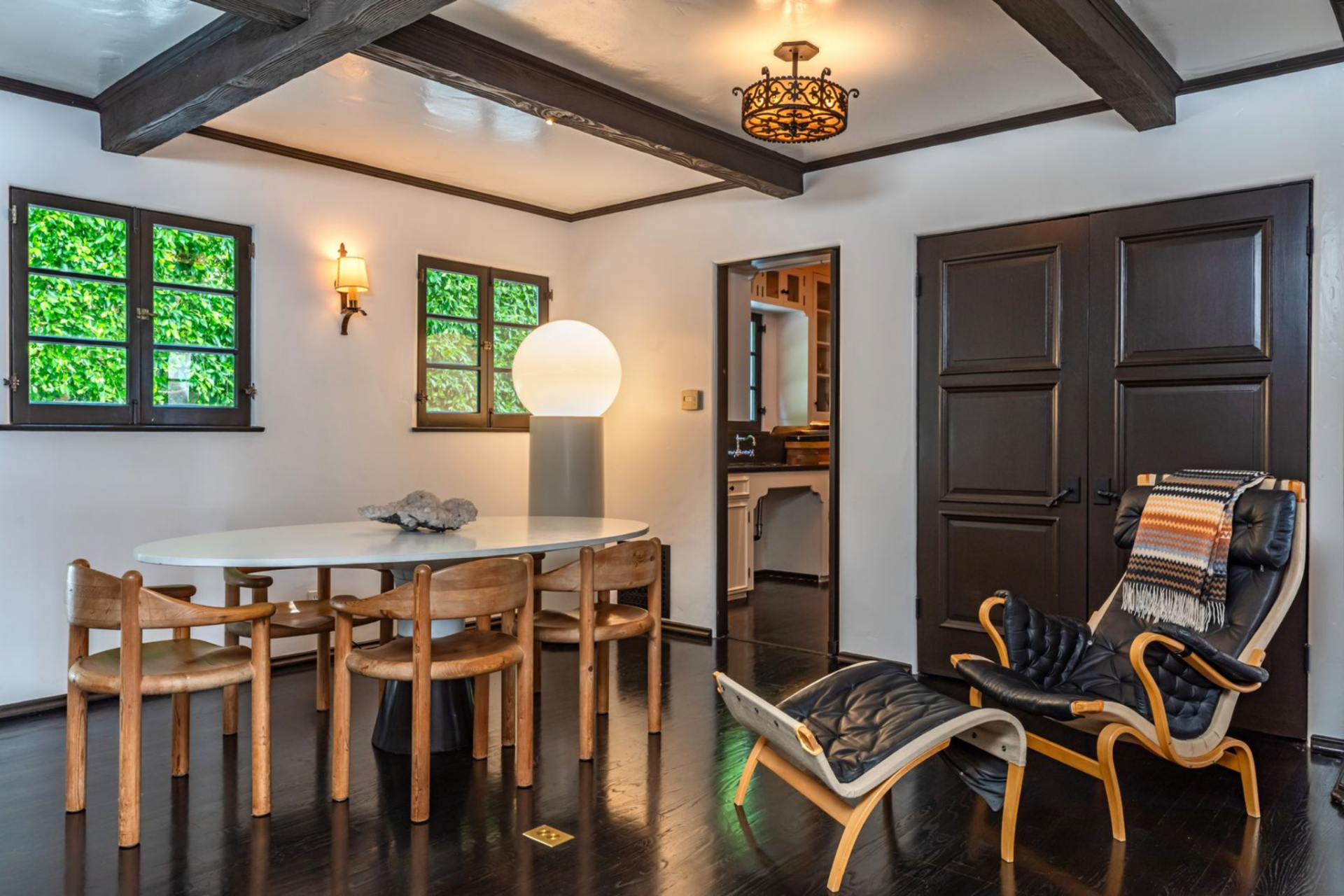 From there, the room opens into a smaller game or card area, where a round table sits beneath another decorative ceiling fixture.