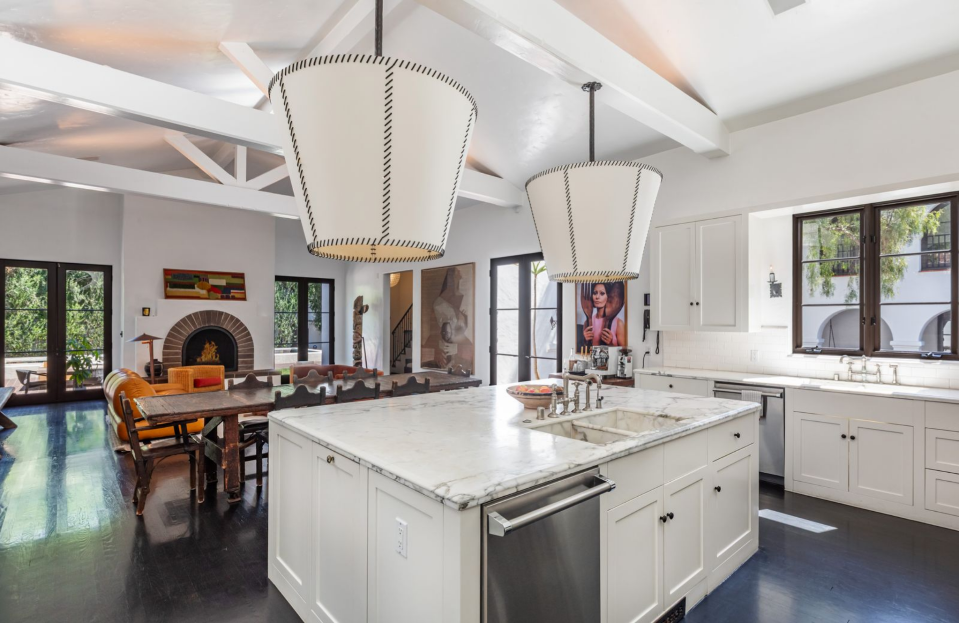 Down the hall, the home opens into a kitchen centered around a large marble island with an integrated sink, surrounded by paneled cabinetry, and a professional range set into a tiled backsplash.