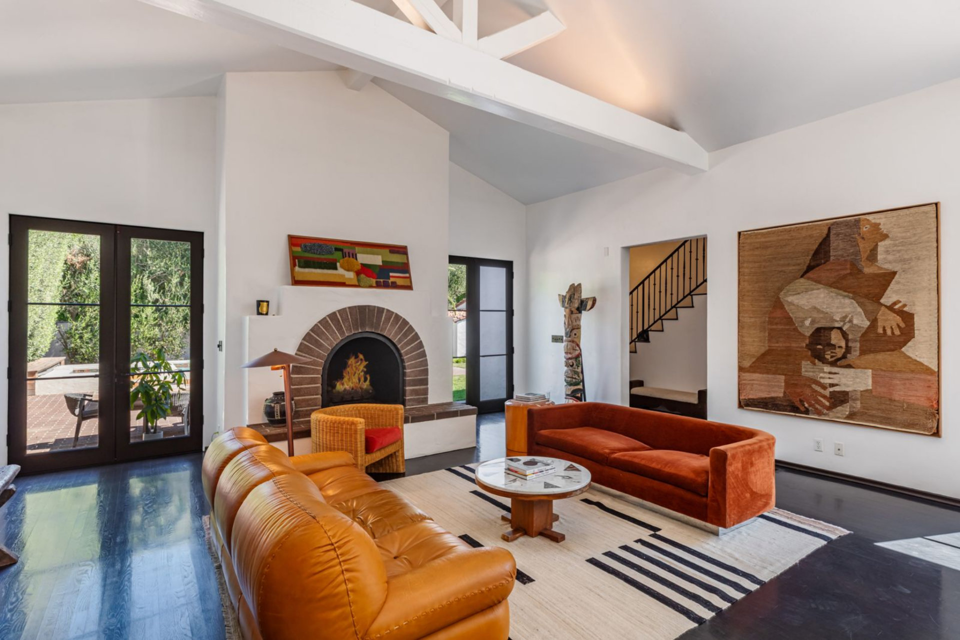 Beyond that, the fireside seating area is arranged around another brick-lined fireplace set into a clean plaster surround, with a mix of leather and upholstered seating facing inward. 
