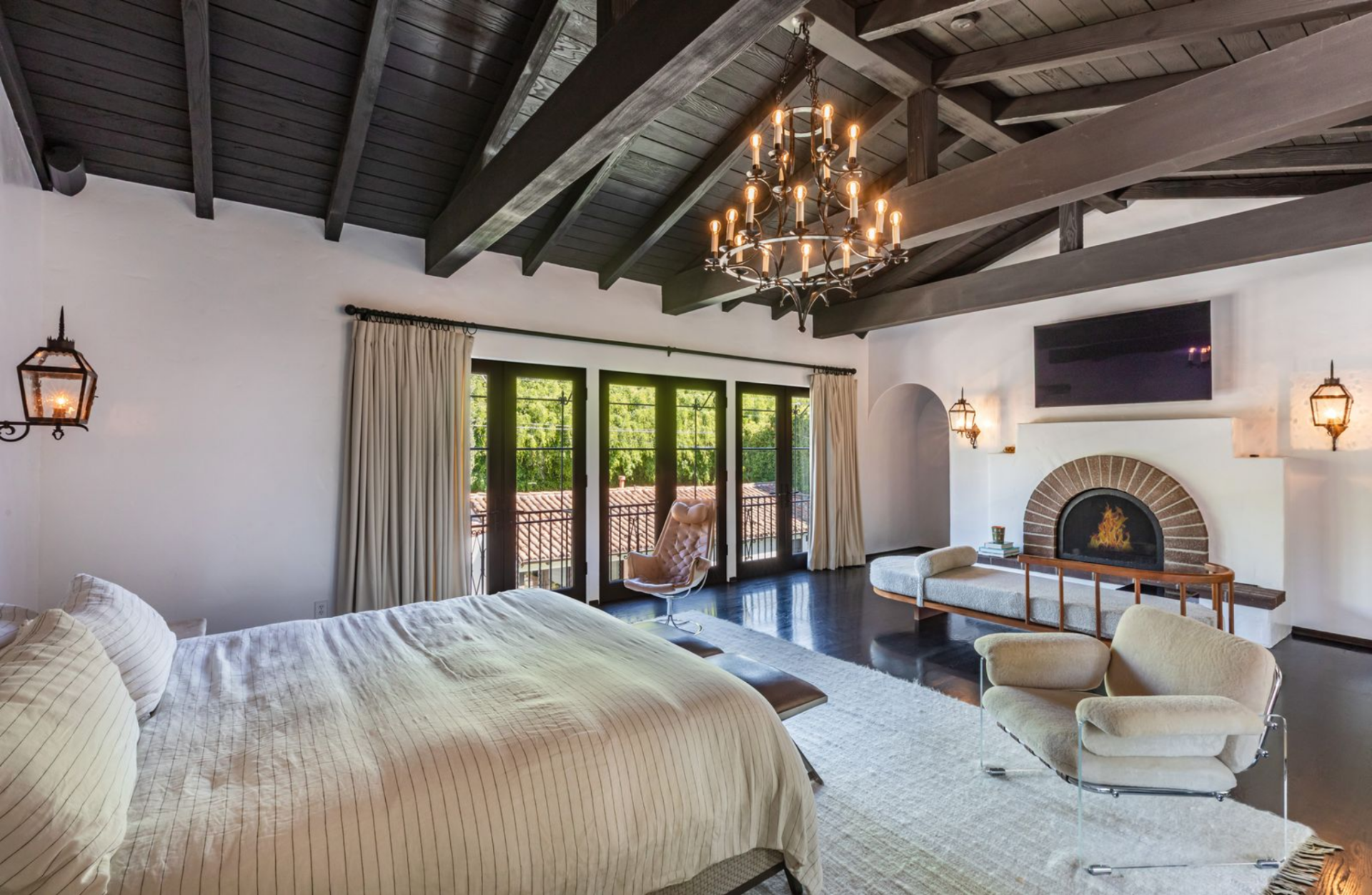 Along one wall, a row of French doors brings in natural light and leads out to a narrow balcony, while the opposite side features a fireside lounge.