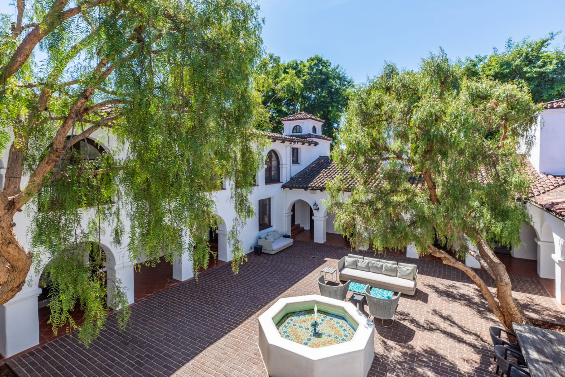 The home follows a Spanish Colonial layout centered around a private brick-lined courtyard that links the surrounding living spaces through a series of arched openings and French doors.