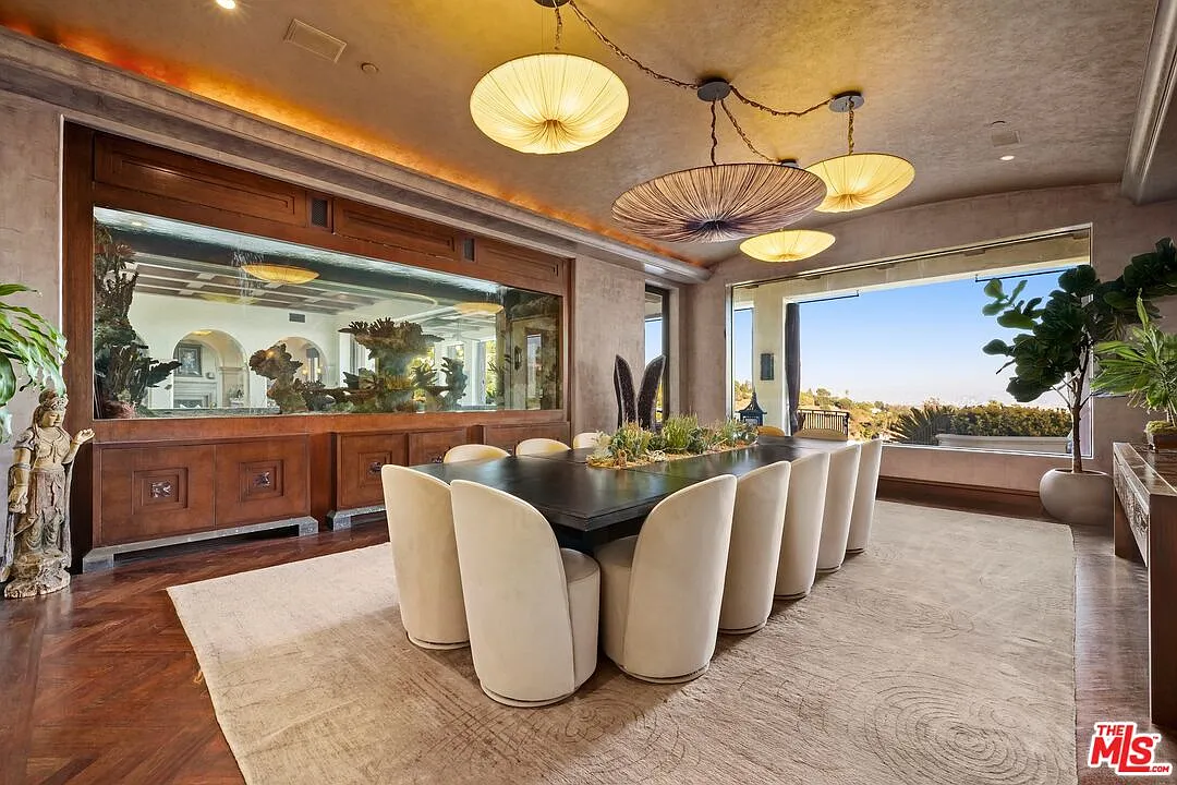 On the other side of the living room, the dining room is made up of a long black table and upholstered chairs beneath a group of sculptural pendant lights.