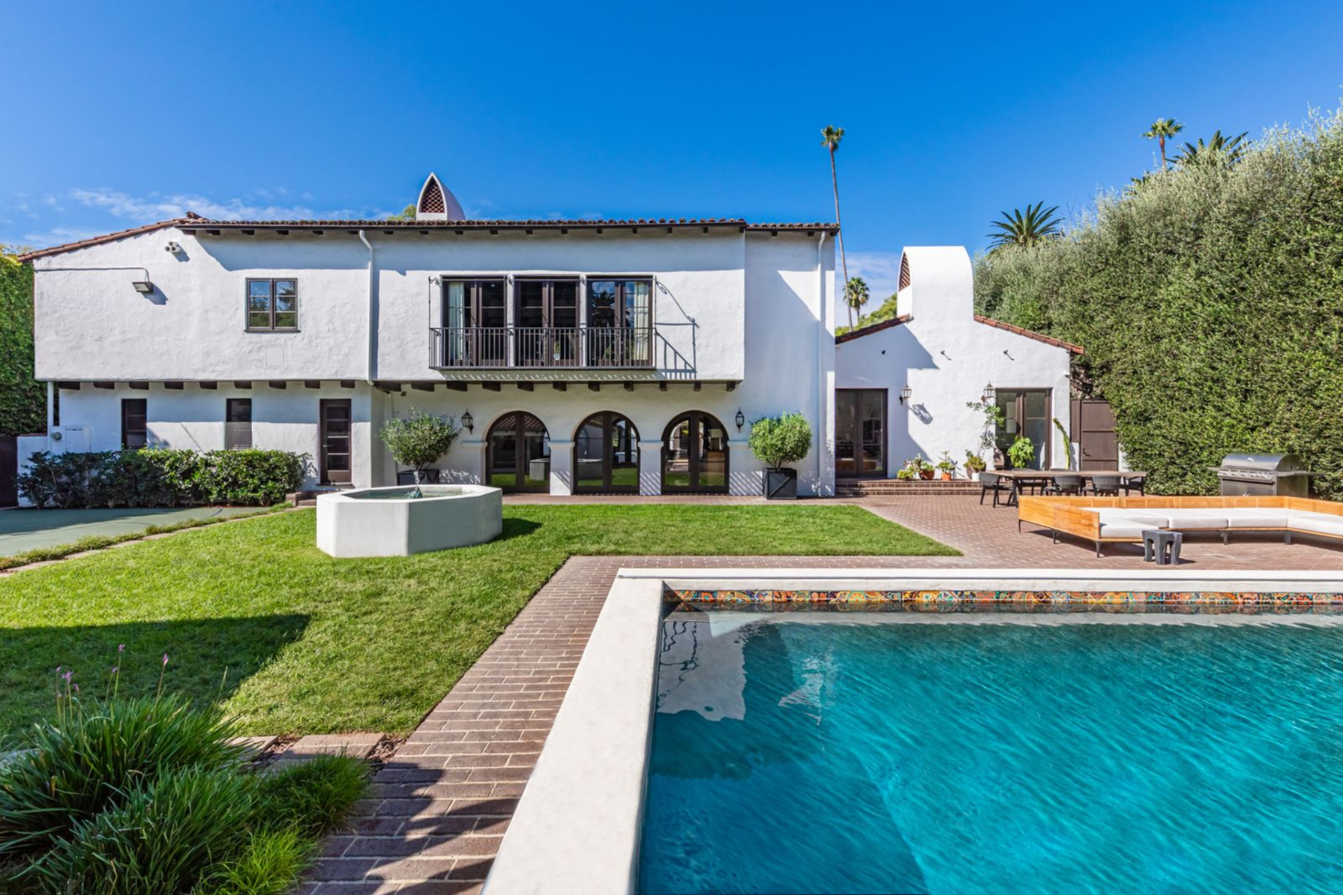 In front of it, a large sectional seating arrangement defines a central gathering area, positioned to face both the water and the home’s rear façade. 