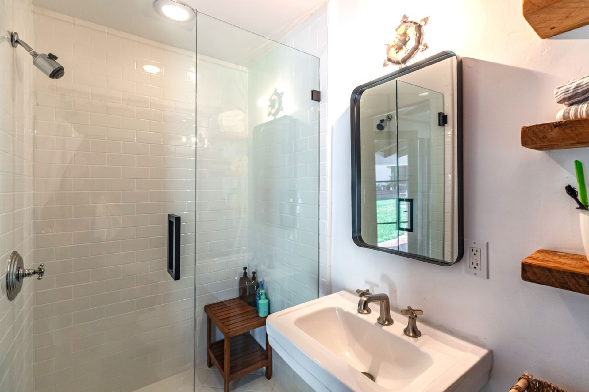 The bathroom is compact and cleanly finished, with a glass-enclosed shower lined in white subway tile. 