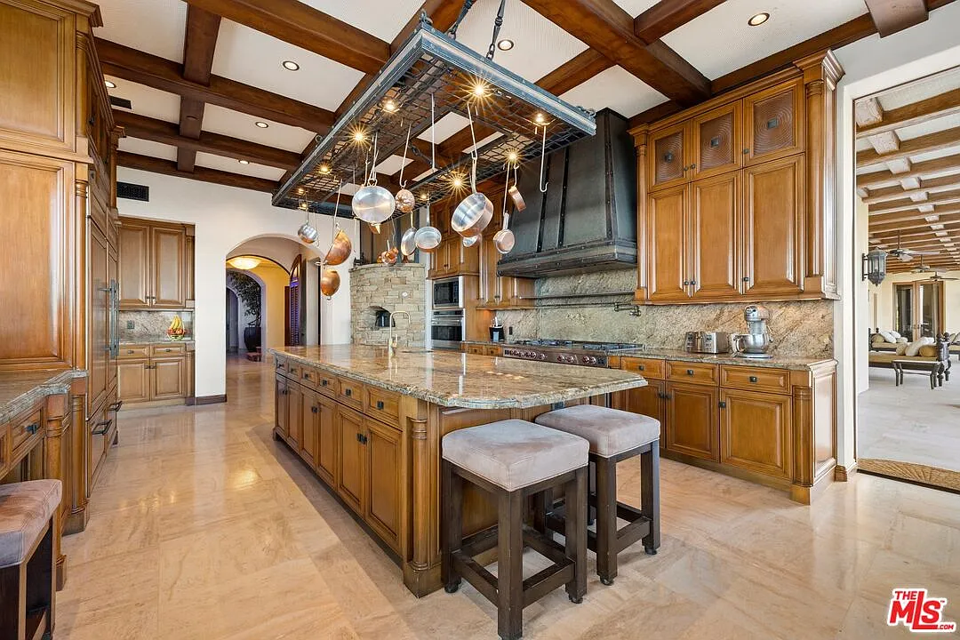 Cabinetry lines the walls on both sides, with a range and oversized hood built into one wall and additional prep space and storage continuing along the other. 