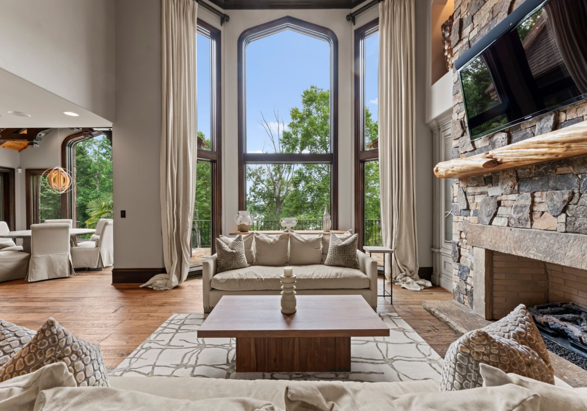 Through the center archway, the home opens into a two-story great room with floor-to-ceiling windows rising behind the main seating area, framing Lake Norman.