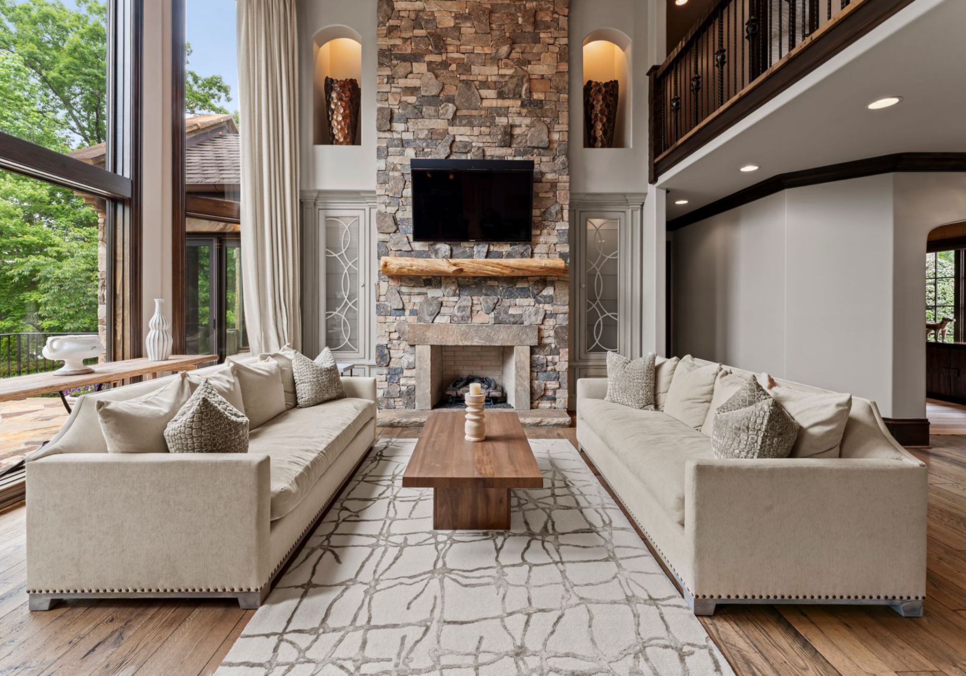 The seating arrangement is centered around a tall stone fireplace, with matching sofas facing each other across a wood coffee table.