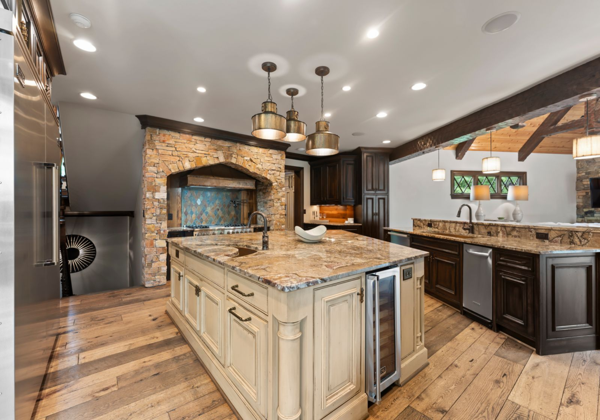 Dark wood cabinetry wraps the perimeter, contrasting with the lighter island and wide-plank floors.