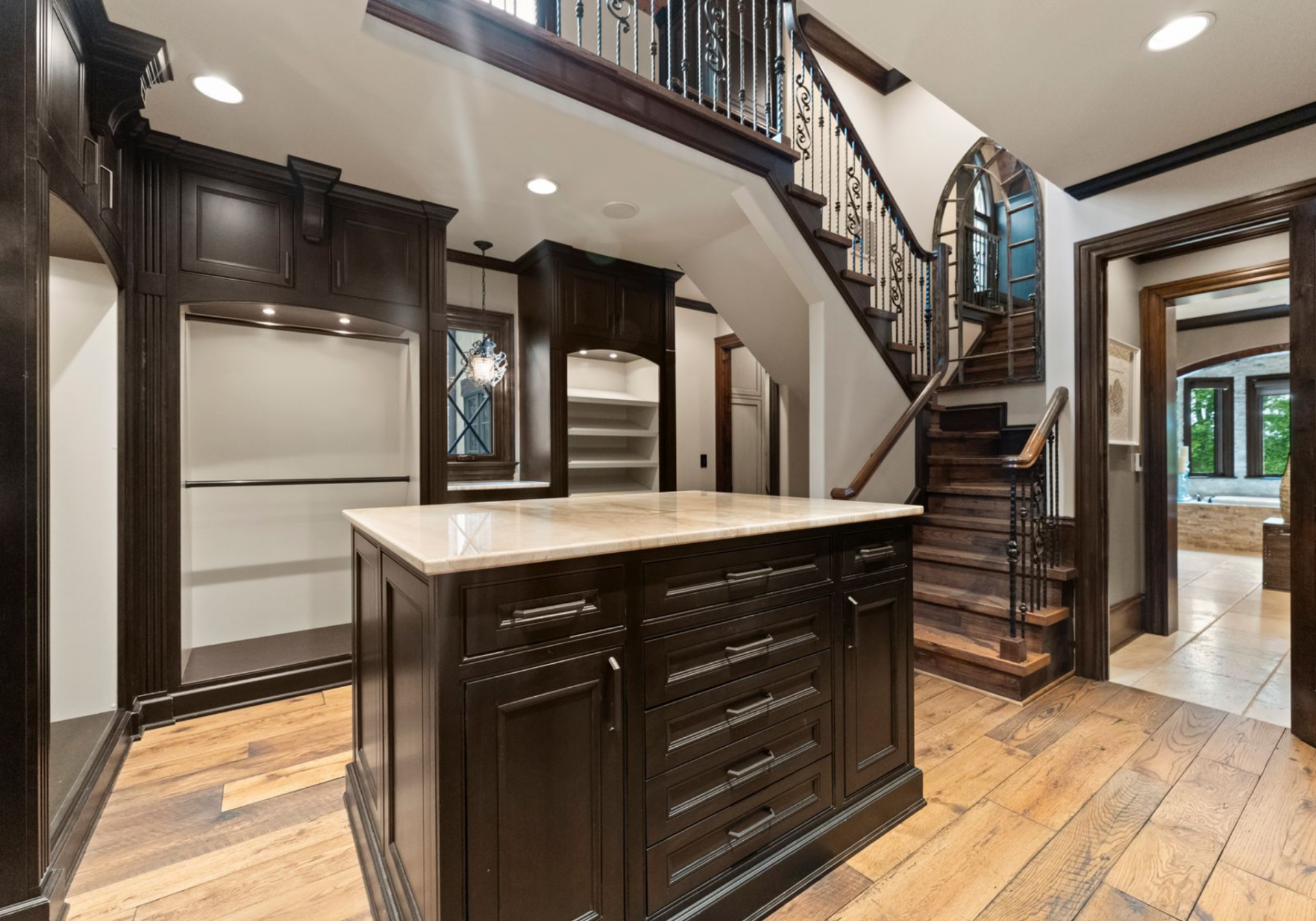 The suite's closet is designed with volume in mind, rising to a second level with custom shelving, built-in storage, and a central island for organization.