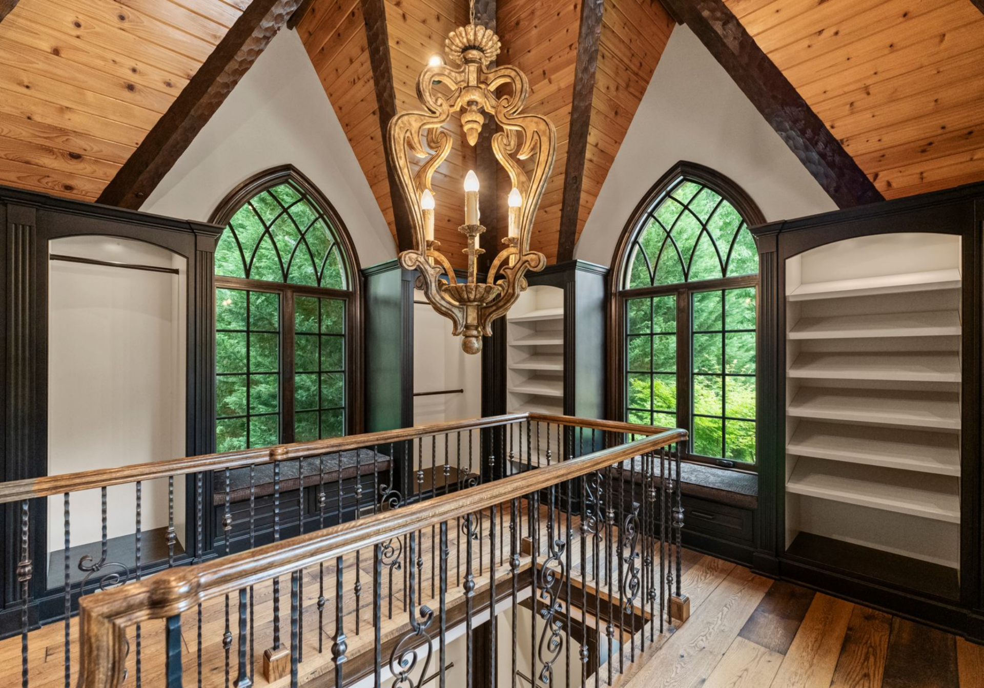A staircase leads to the upper level, where additional wardrobe space lines both sides beneath vaulted ceilings and arched windows.