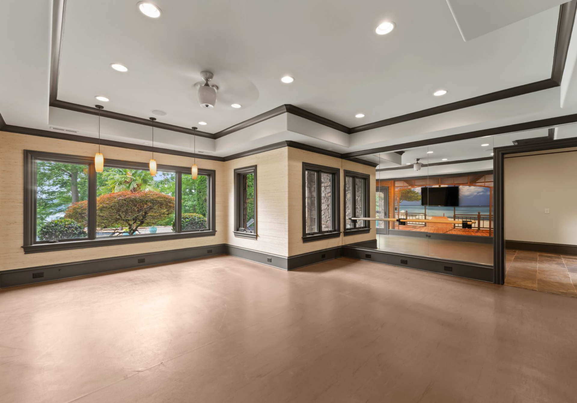 The gym sits in a large mirrored room with multiple windows and recessed lighting, making it flexible enough for equipment, stretching, or open workouts.