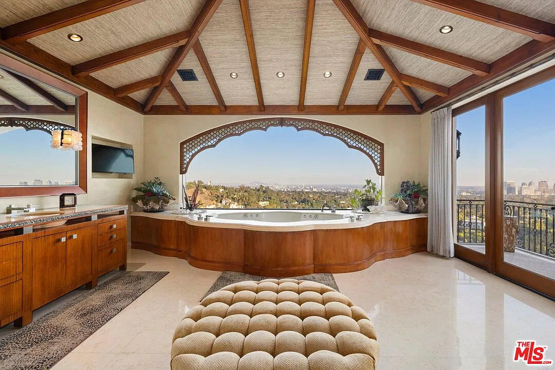 In the suite's bathroom, the exposed wood beams and intricate detailing add a sense of rustic sophistication to the obvious showstopper: a large jacuzzi tub that sits in front of a large window framing the city.