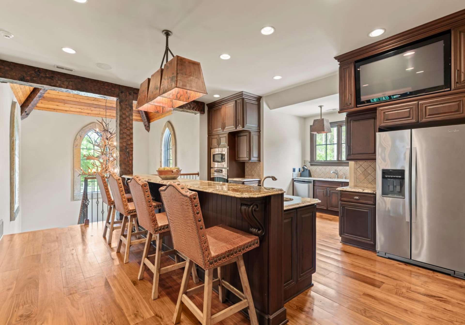 The apartment opens with a compact kitchen built around dark wood cabinetry, granite counters, and a raised breakfast bar.
