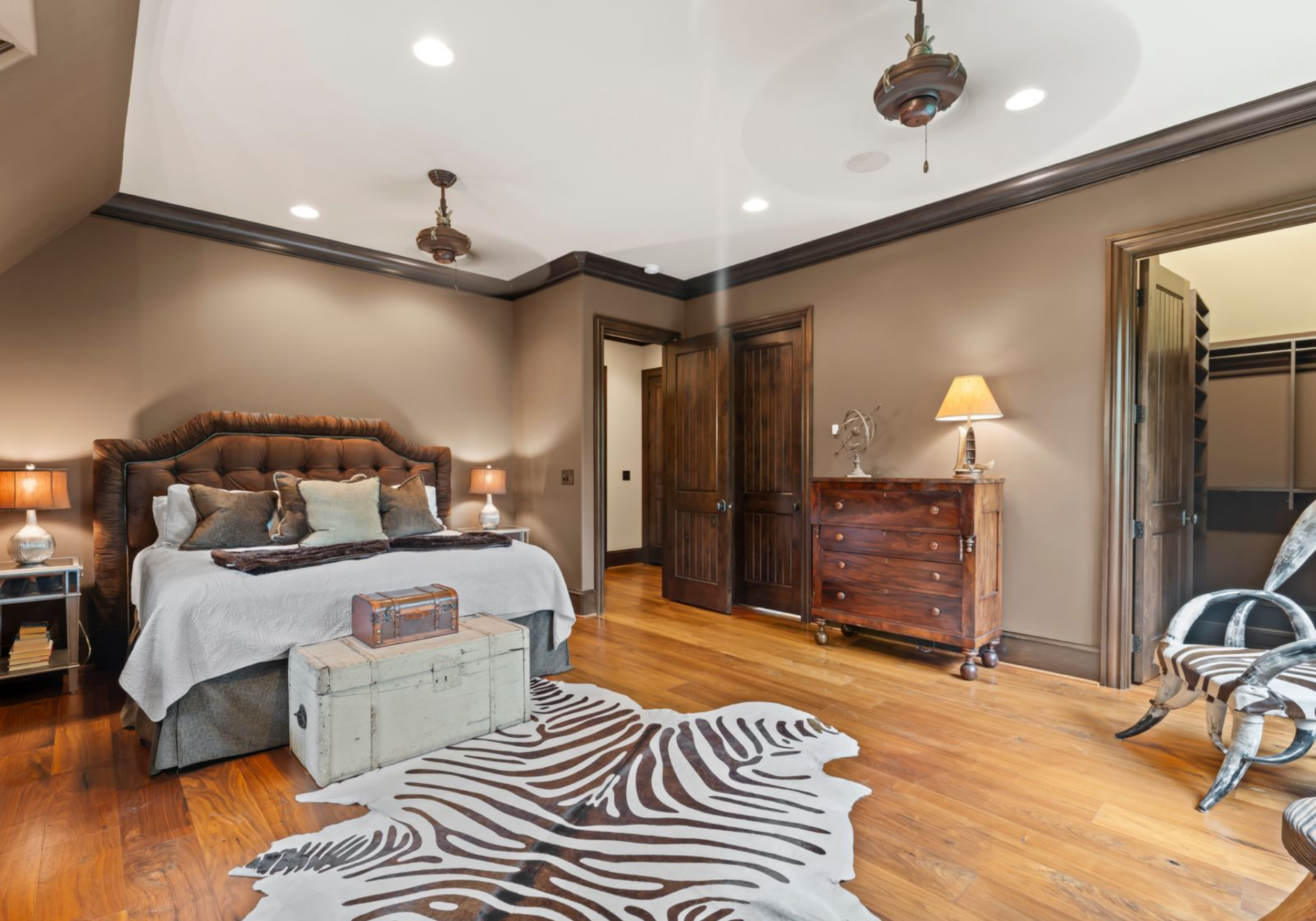 A leather headboard, vintage-style chest, and hide rug continue the apartment’s Western-inspired look while keeping the space practical for overnight guests.