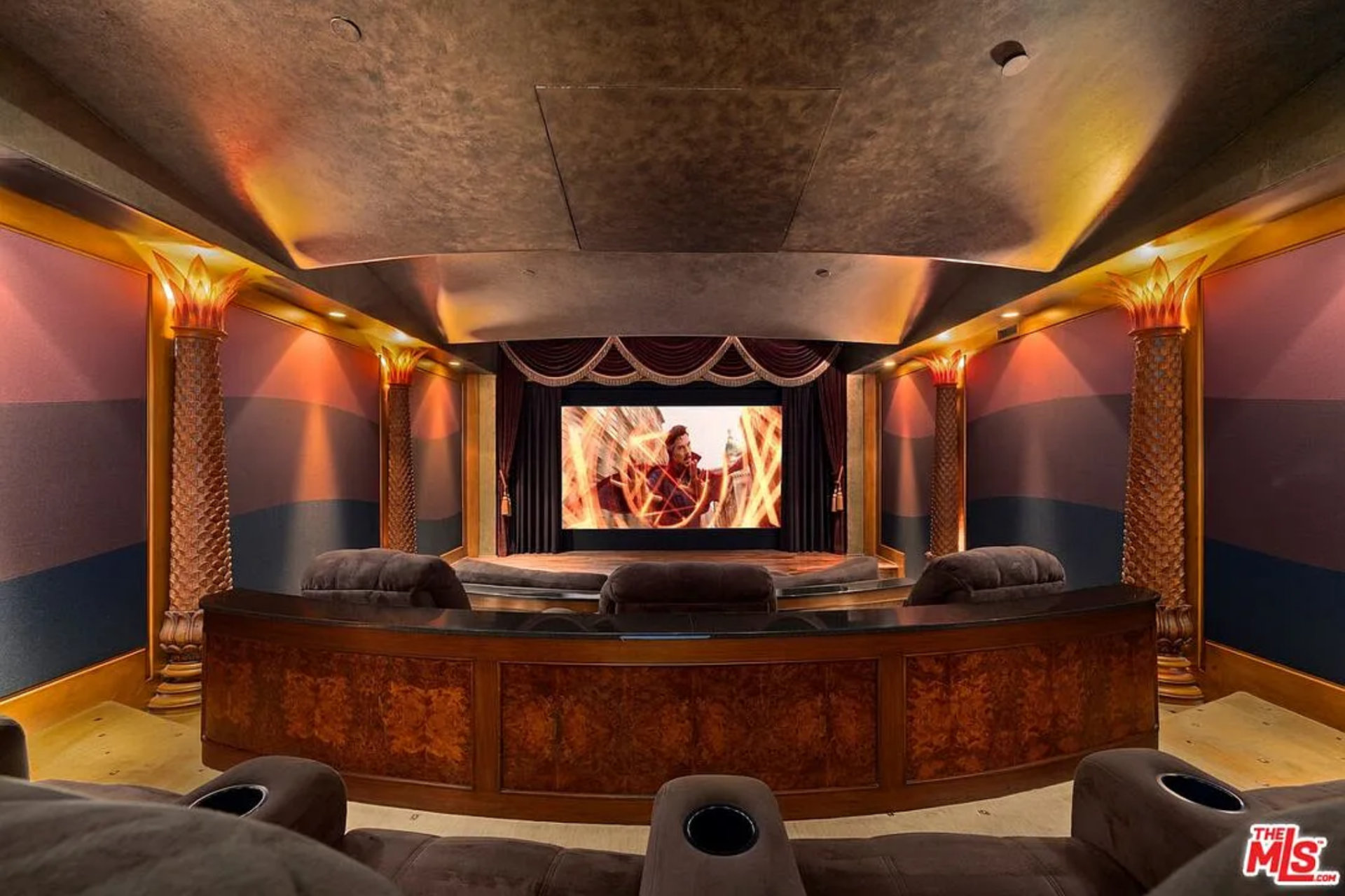One of the home's interior amenities, the private theater is designed like a classic screening room, with the screen framed by dark drapery and a raised platform below.