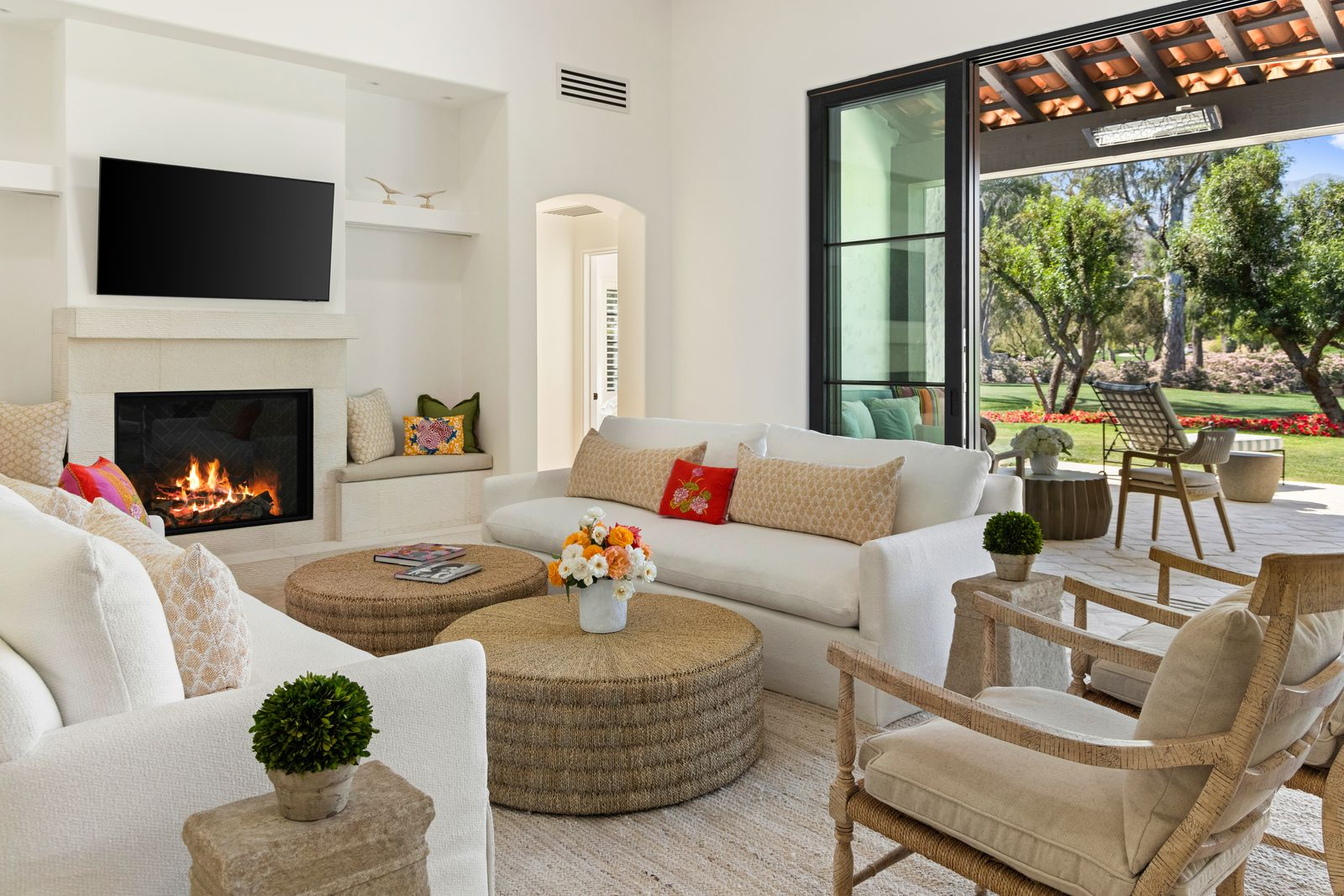 One side of the room is the living area, featuring a sleek fireplace set beneath a mounted television and framed by built-in bench seating.